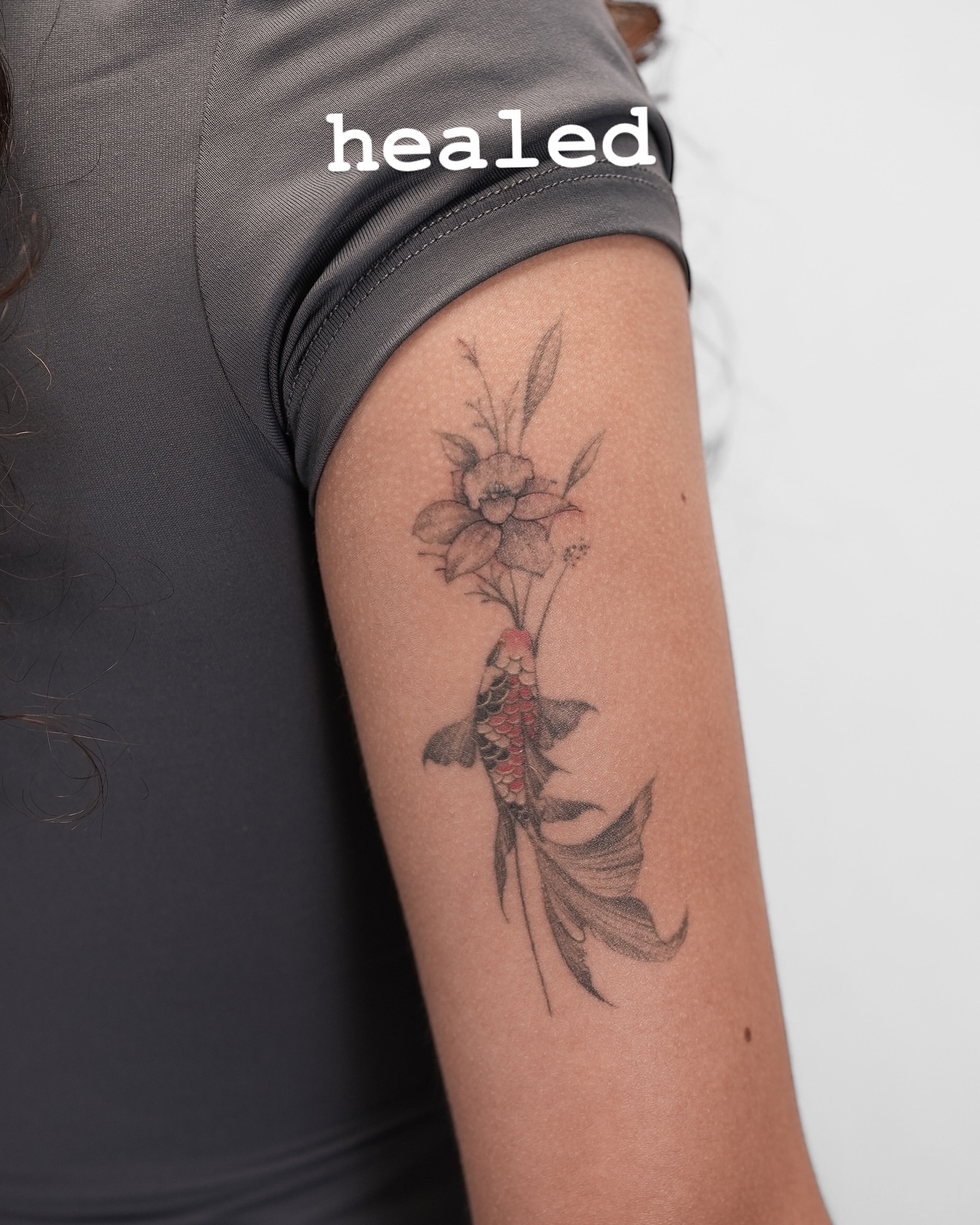 Koi fish and flower black and grey tattoo on the forearm by X