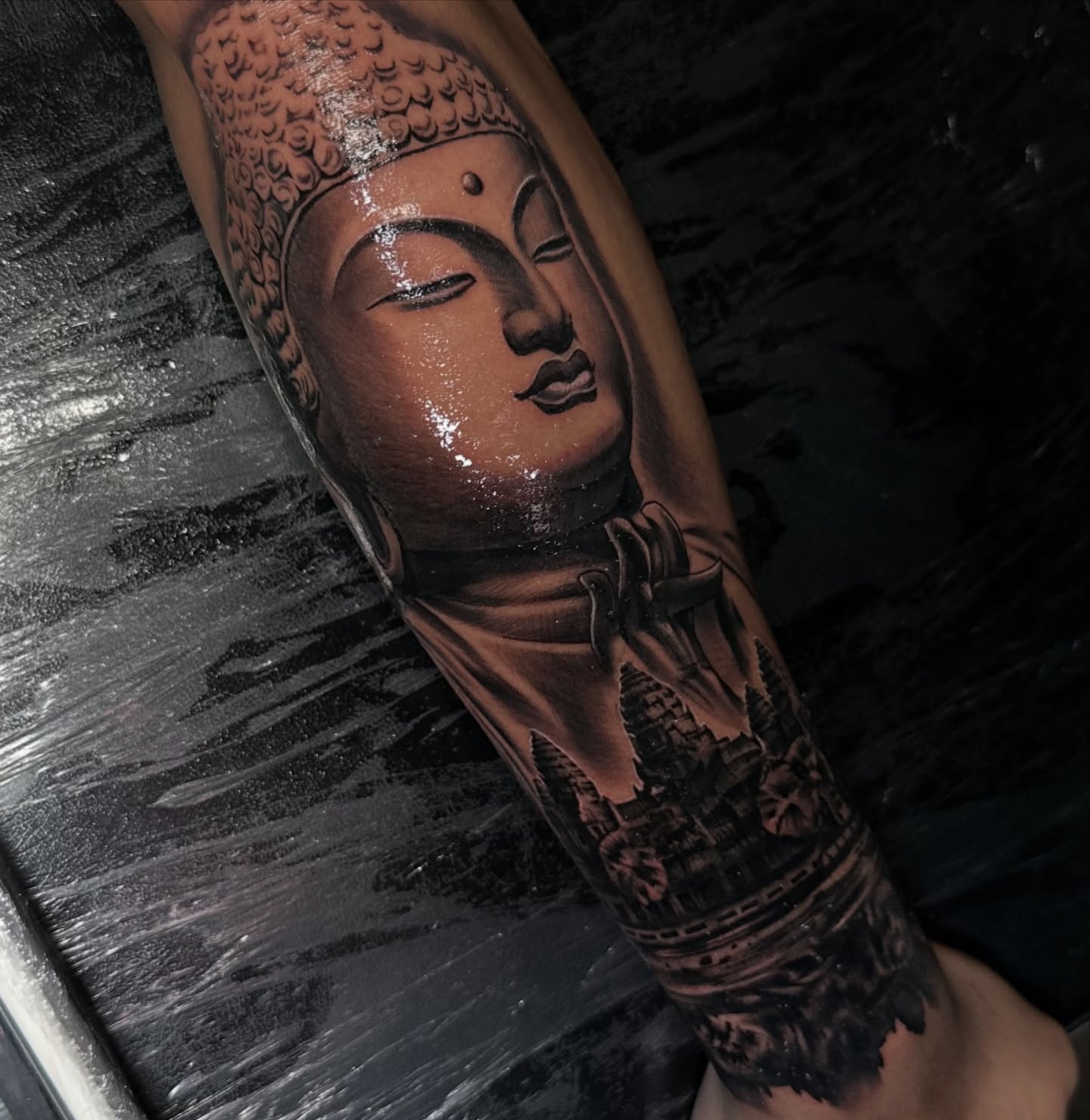 Buddha head realism tattoo on the forearm by Mando