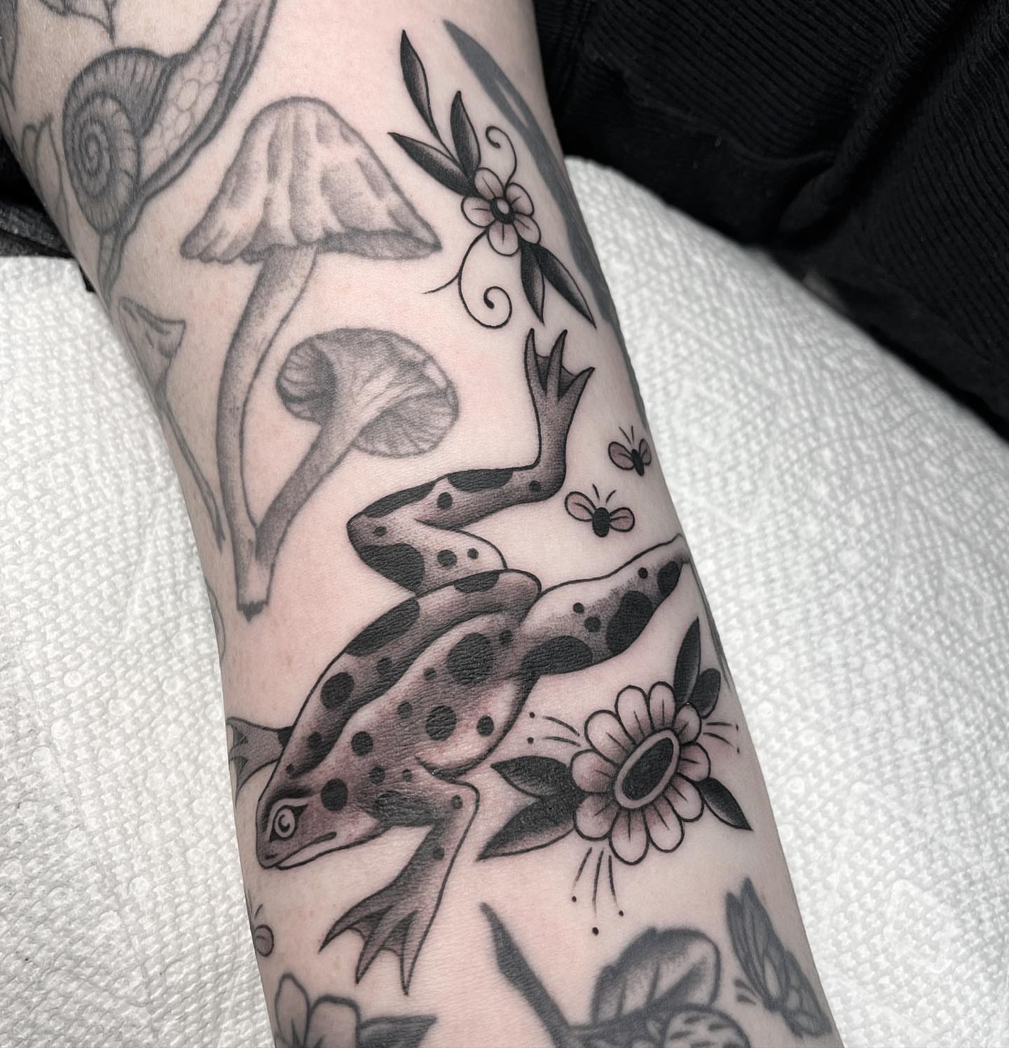 Frog and mushrooms American traditional tattoo on the forearm by Kayla Faircloth, Charlotte, North Carolina
