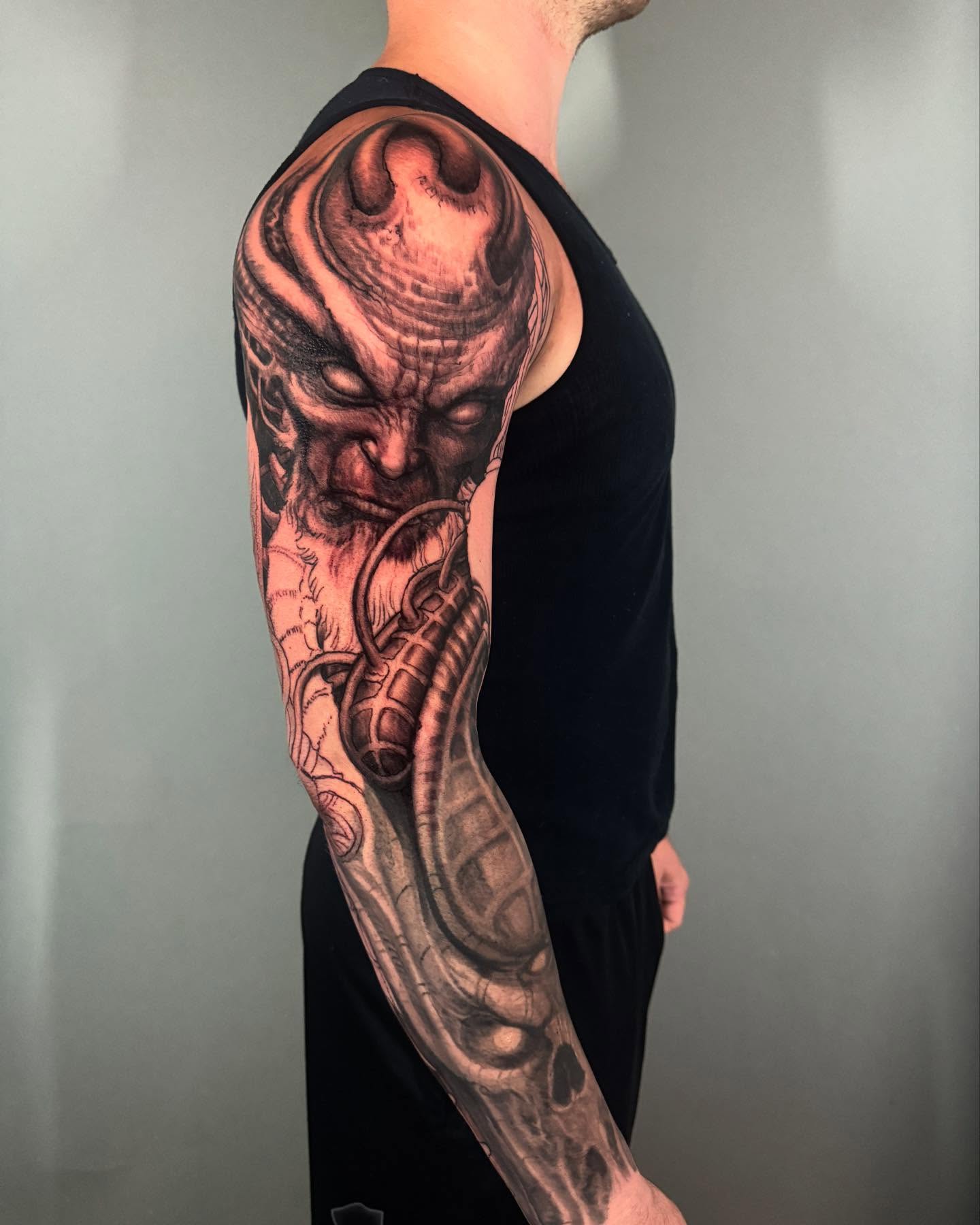 Demon with gun dark realism tattoo on the forearm by Paul Booth