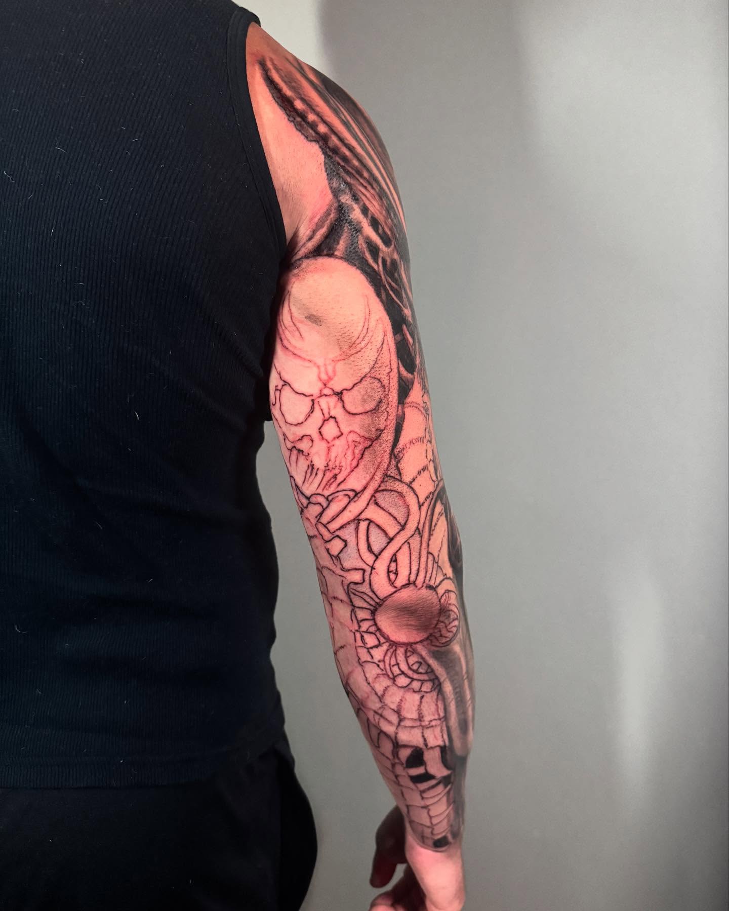 Skull and snake realism tattoo on the upper arm by Paul Booth