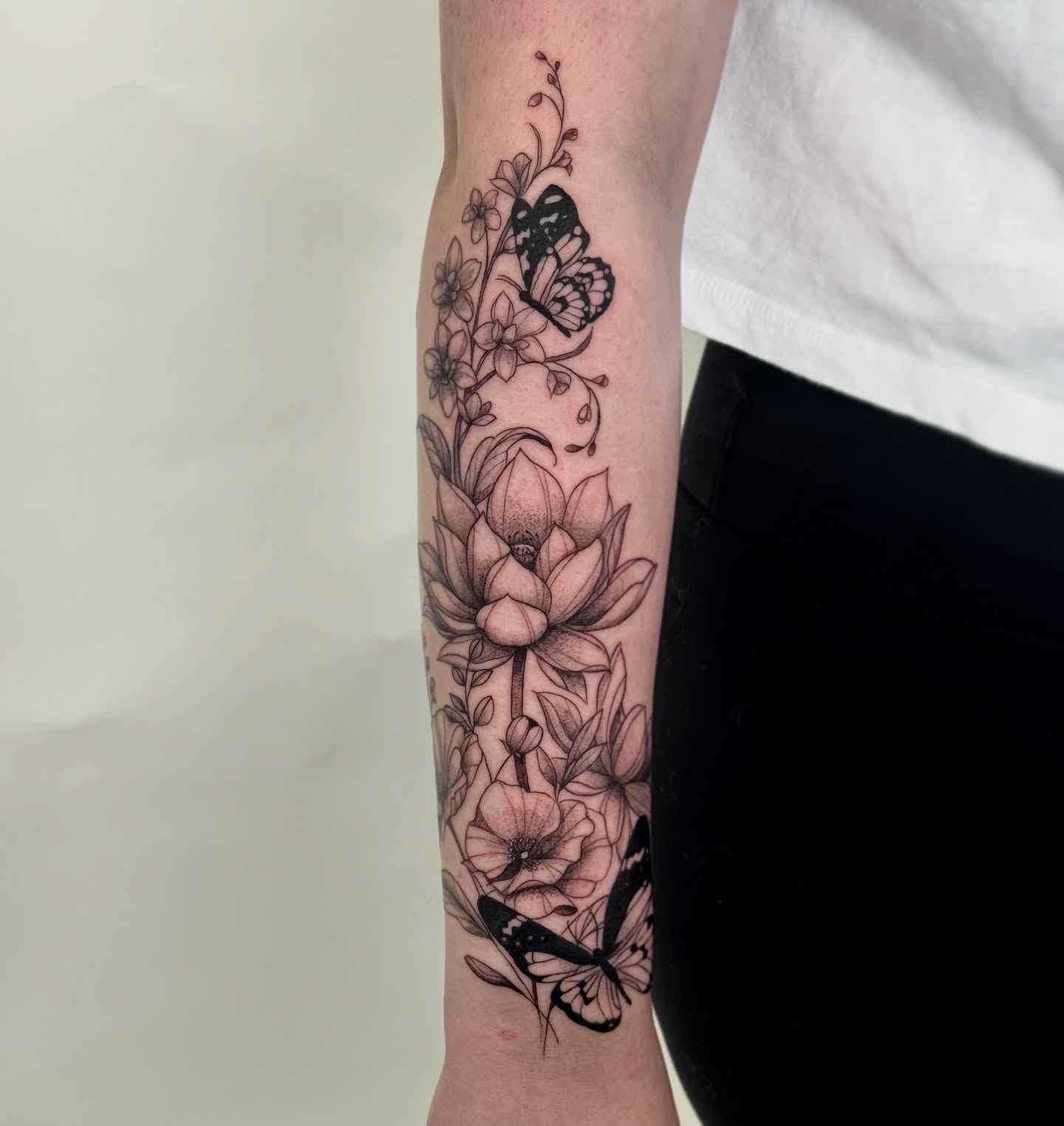 Butterfly and lotus dotwork tattoo on the forearm by Brisia Cisneros
