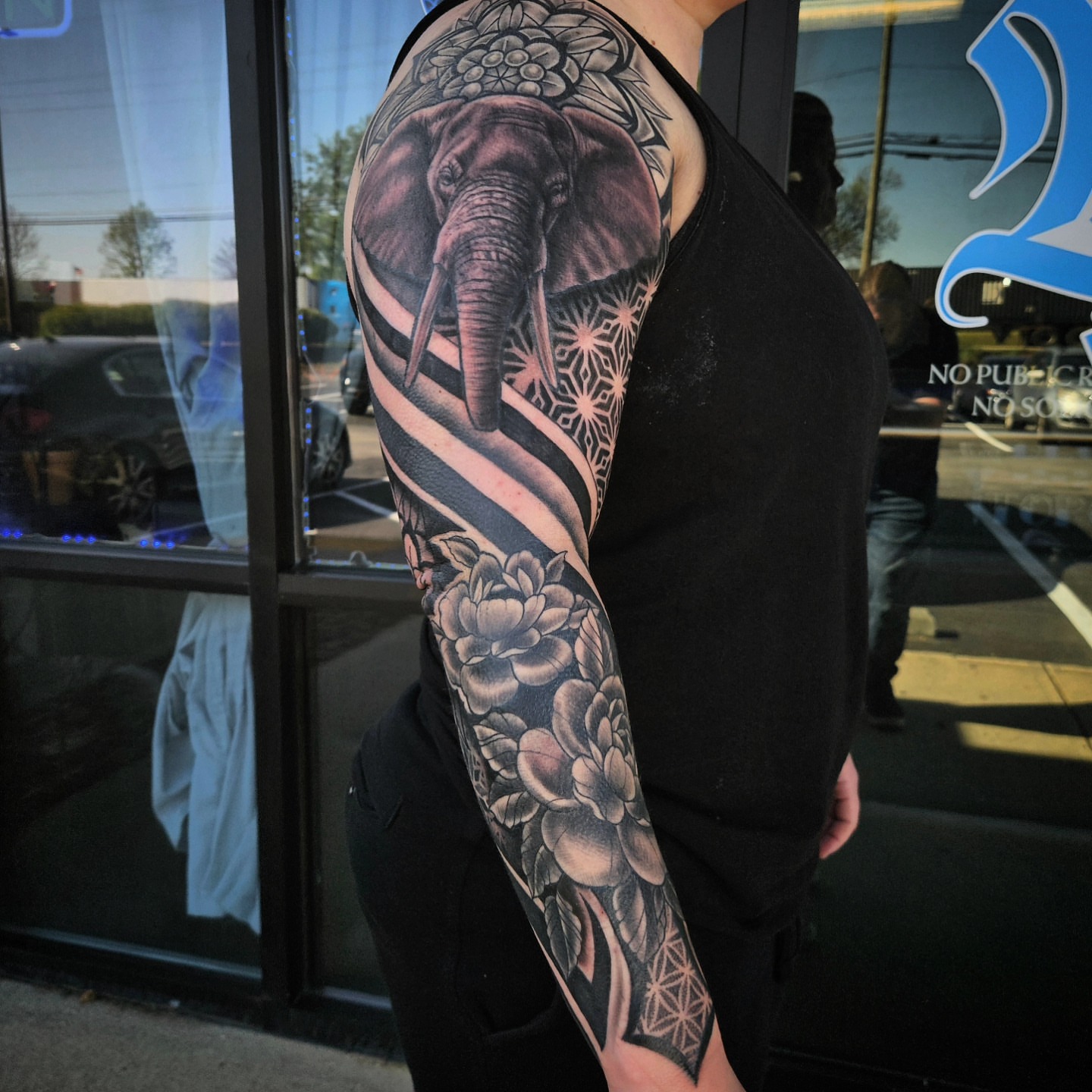 Elephant and floral geometric tattoo on the upper arm by Mike Bugenhagen