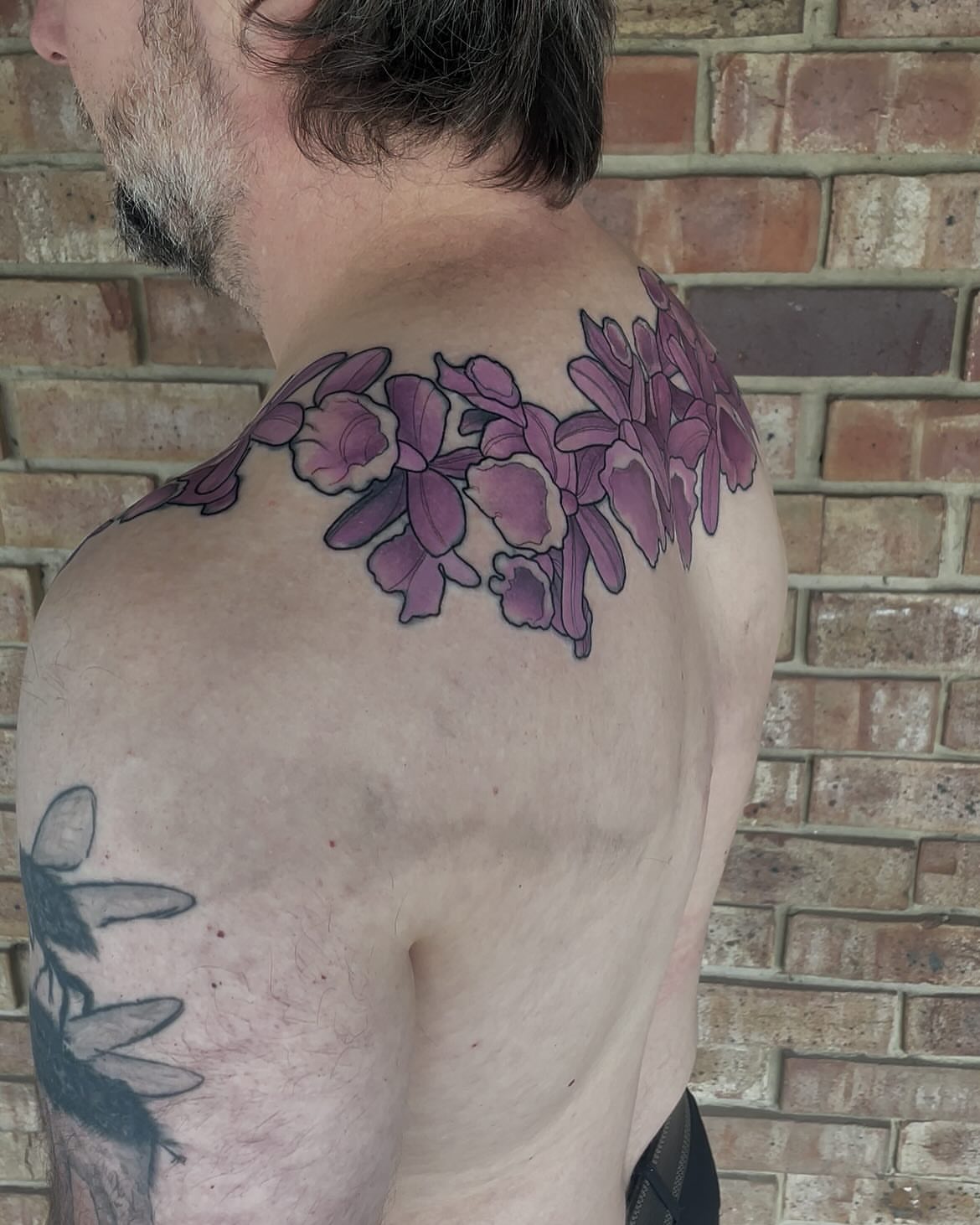 Purple orchids realism tattoo on the shoulder by Nathan Evans