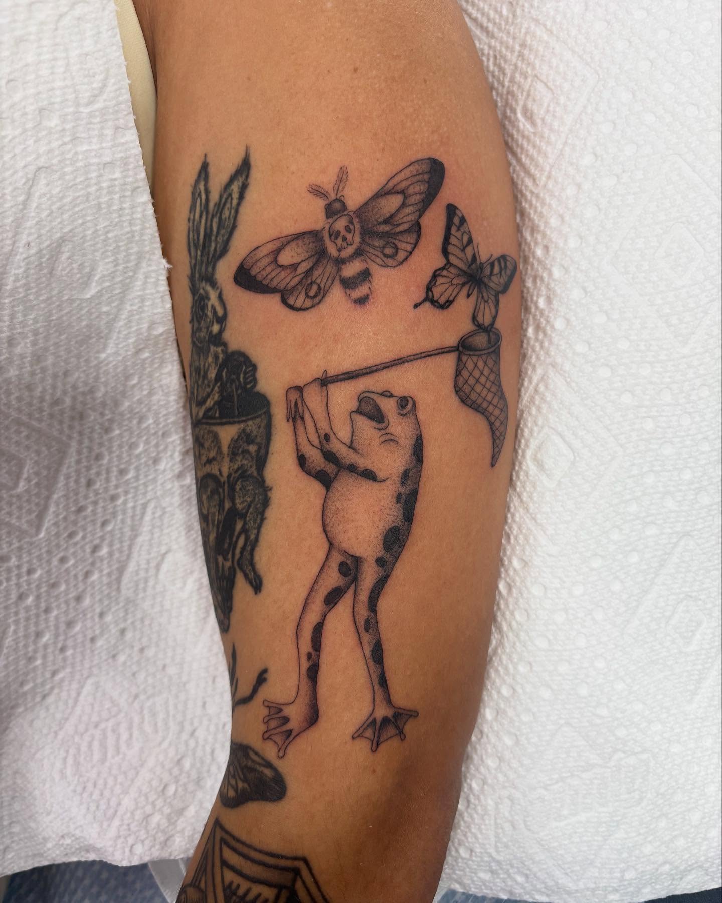 Frog with butterfly net black and grey tattoo on the forearm by ⟡ Sam O ⟡