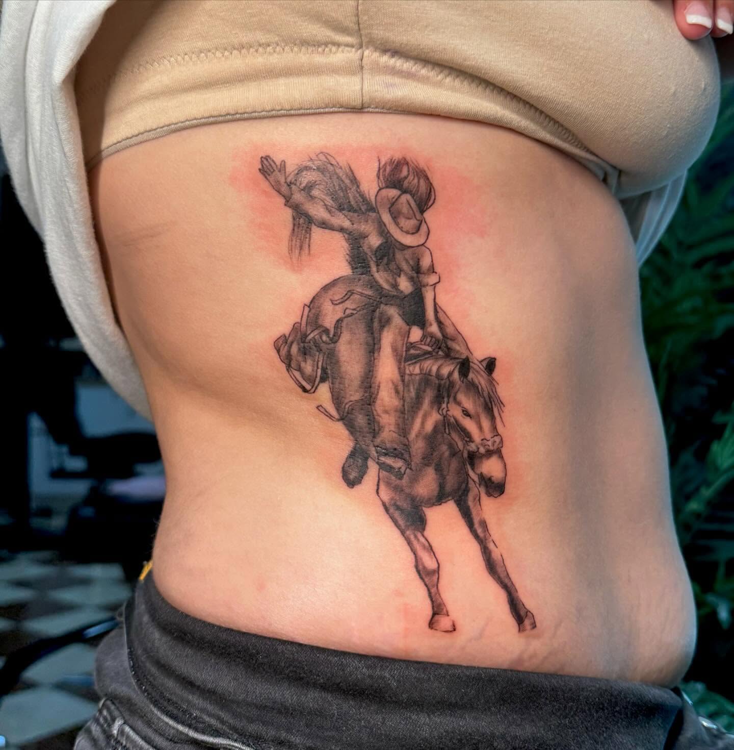 Cowboy riding horse black and grey tattoo on the ribs by Nina Rush