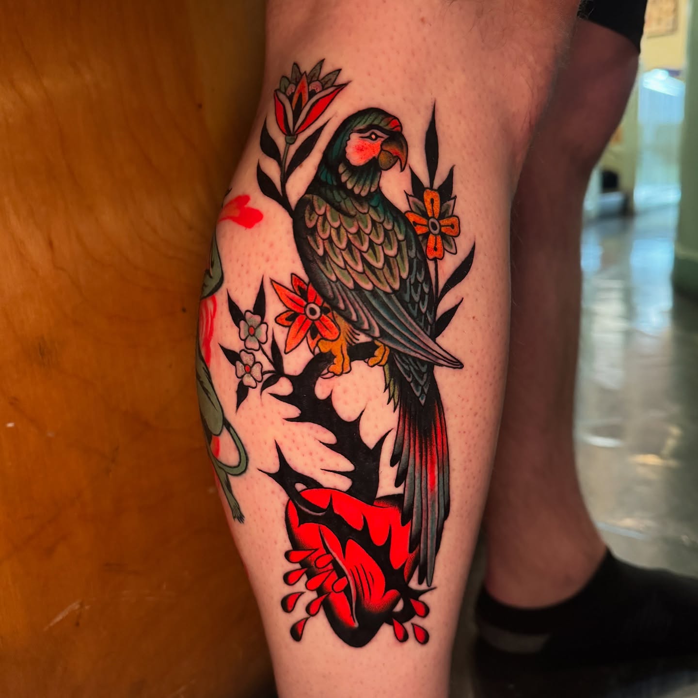 Parrot and flowers American traditional tattoo on the thigh by Pavel