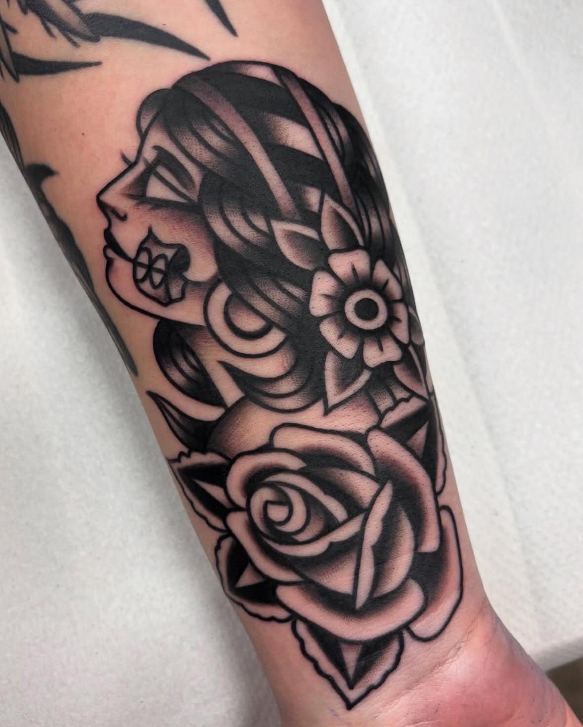 Woman with roses American traditional tattoo on the forearm by Arturo Ledesma