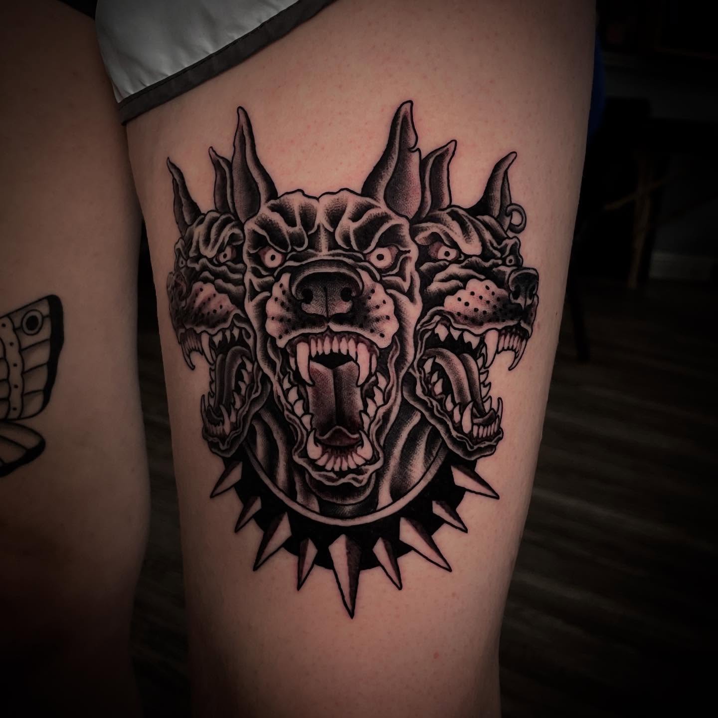 Demon head black and grey tattoo on the thigh by Caleb Baker