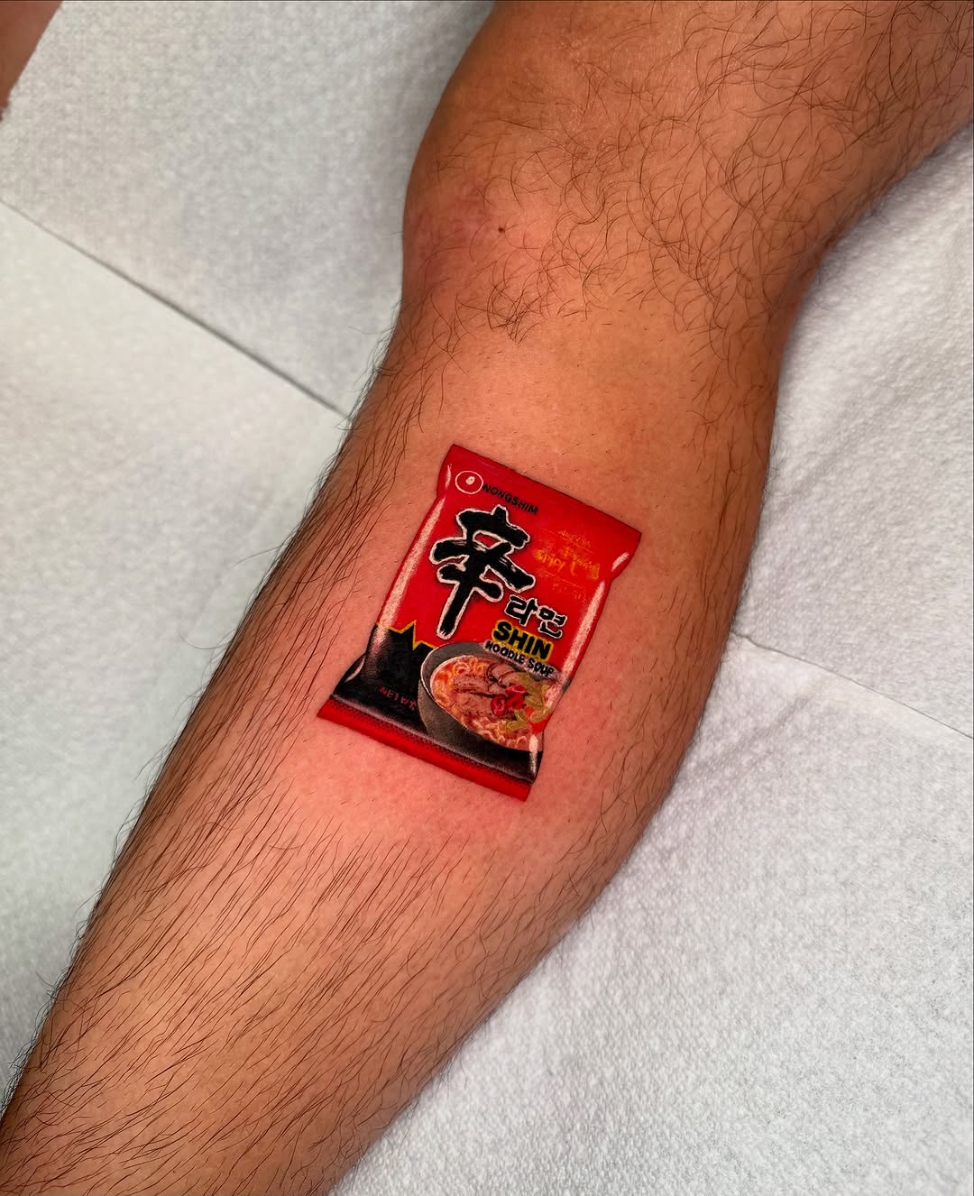 Shin Ramyun noodle soup packet watercolor tattoo on the forearm by Tatum