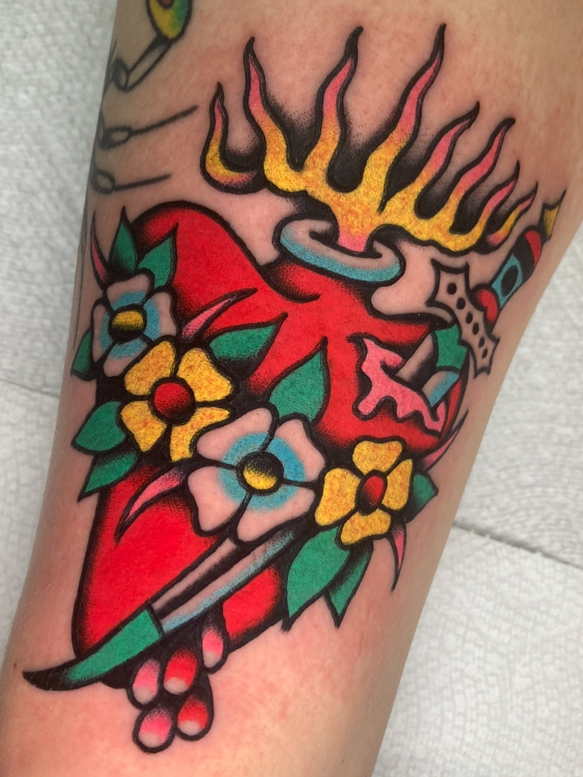 Heart with flames and flowers American traditional tattoo on the forearm by π΅ππππ π¬ππππ