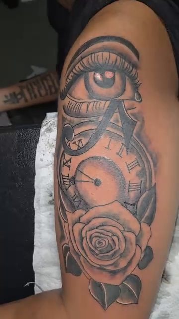 Eye, clock, and rose tattoo surrealism tattoo on the upper arm by Trent Johnson