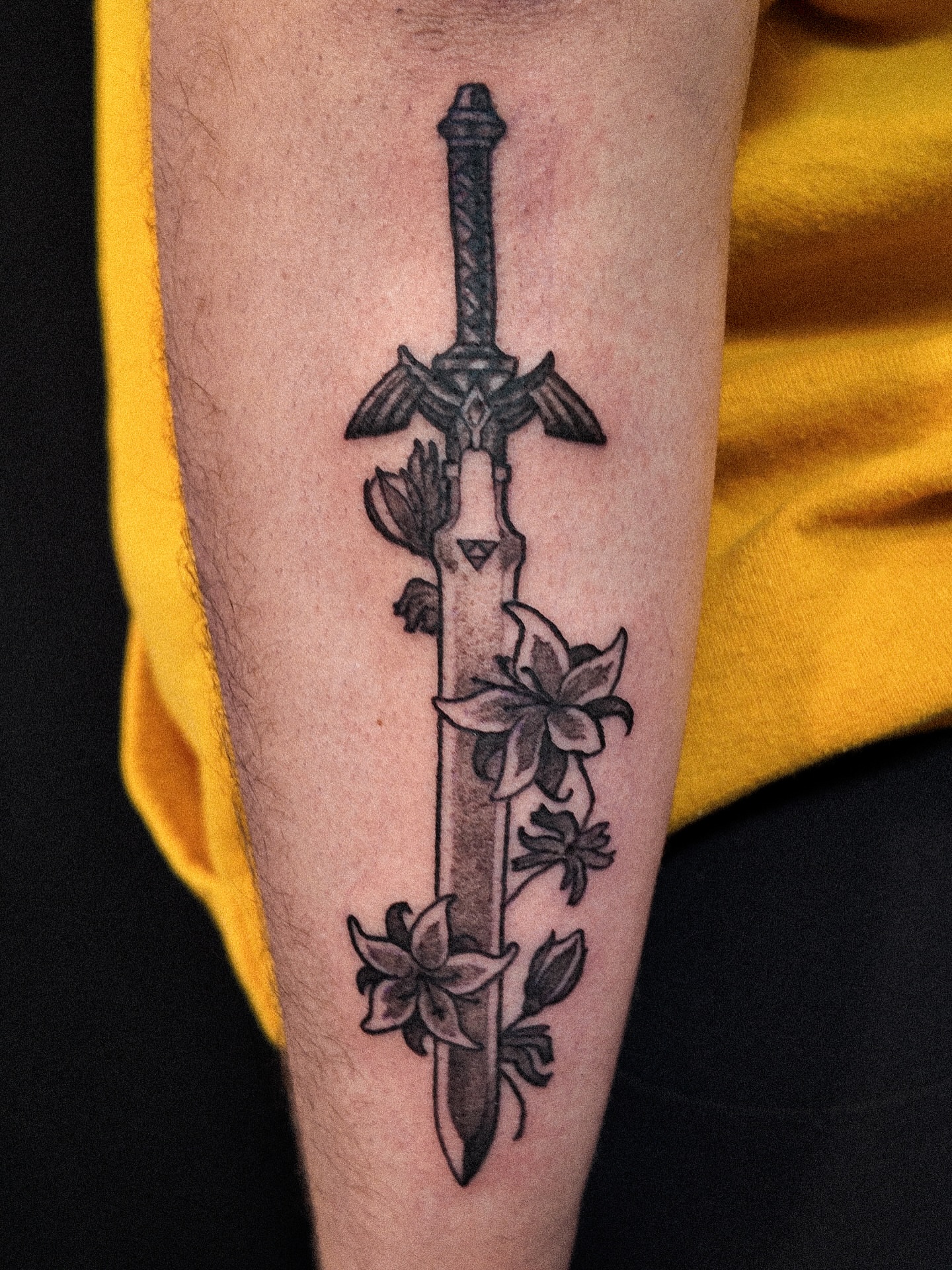 Sword with flowers black and grey tattoo on the forearm by Ben Cisek