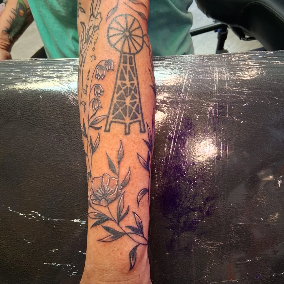 Windmill and floral black and grey tattoo on the forearm by Dave Johnson, Billings, Montana