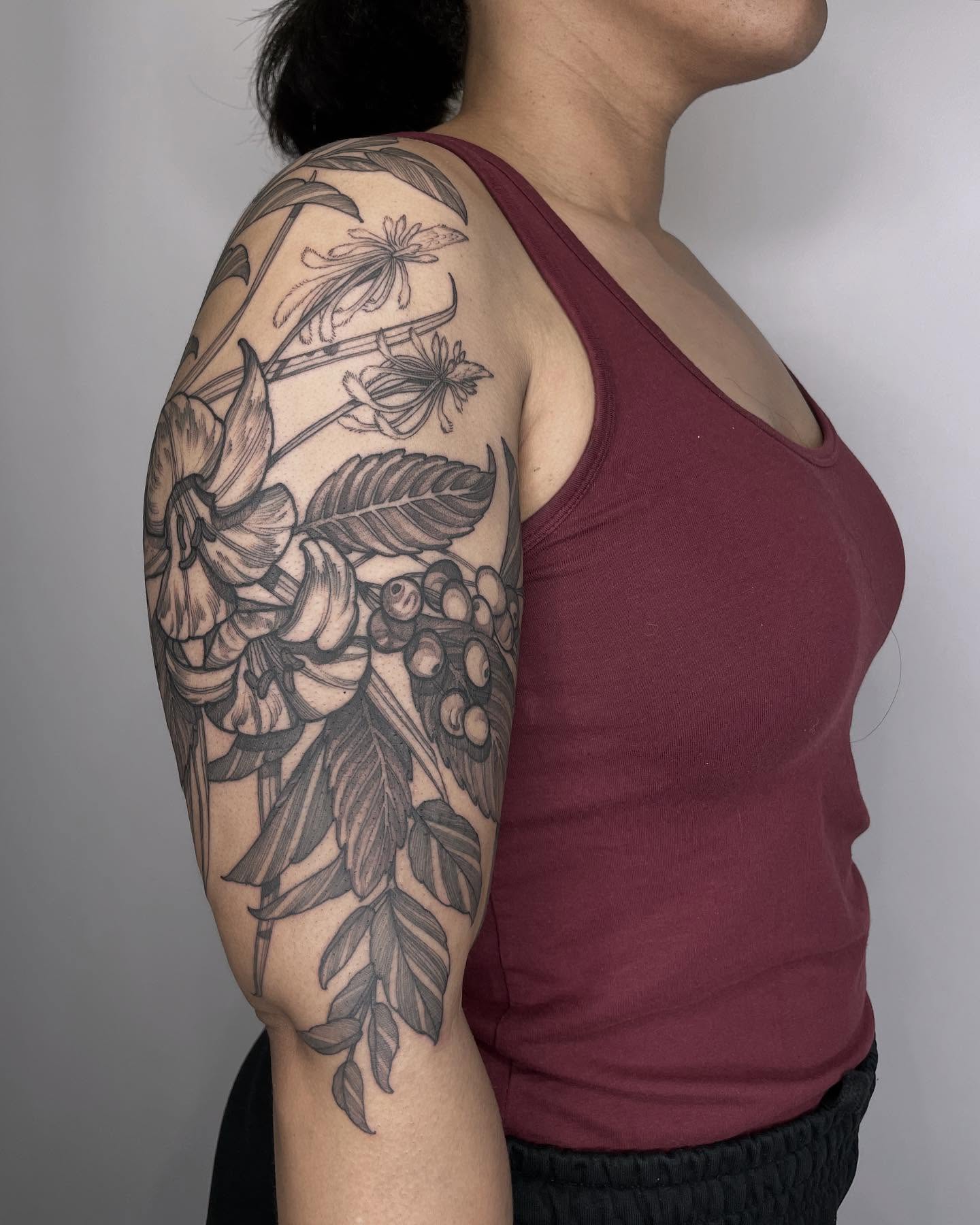 Botanical black and grey tattoo on the upper arm by Carol Jacky