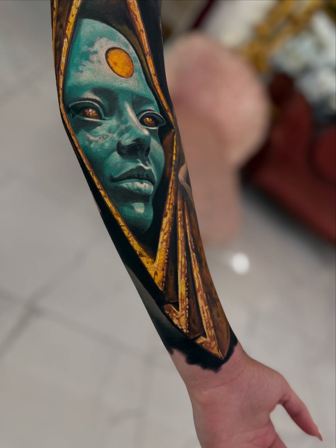 Alien face with sun symbol surrealism tattoo on the forearm by Jacob Sheffield, Grand Junction, Colorado