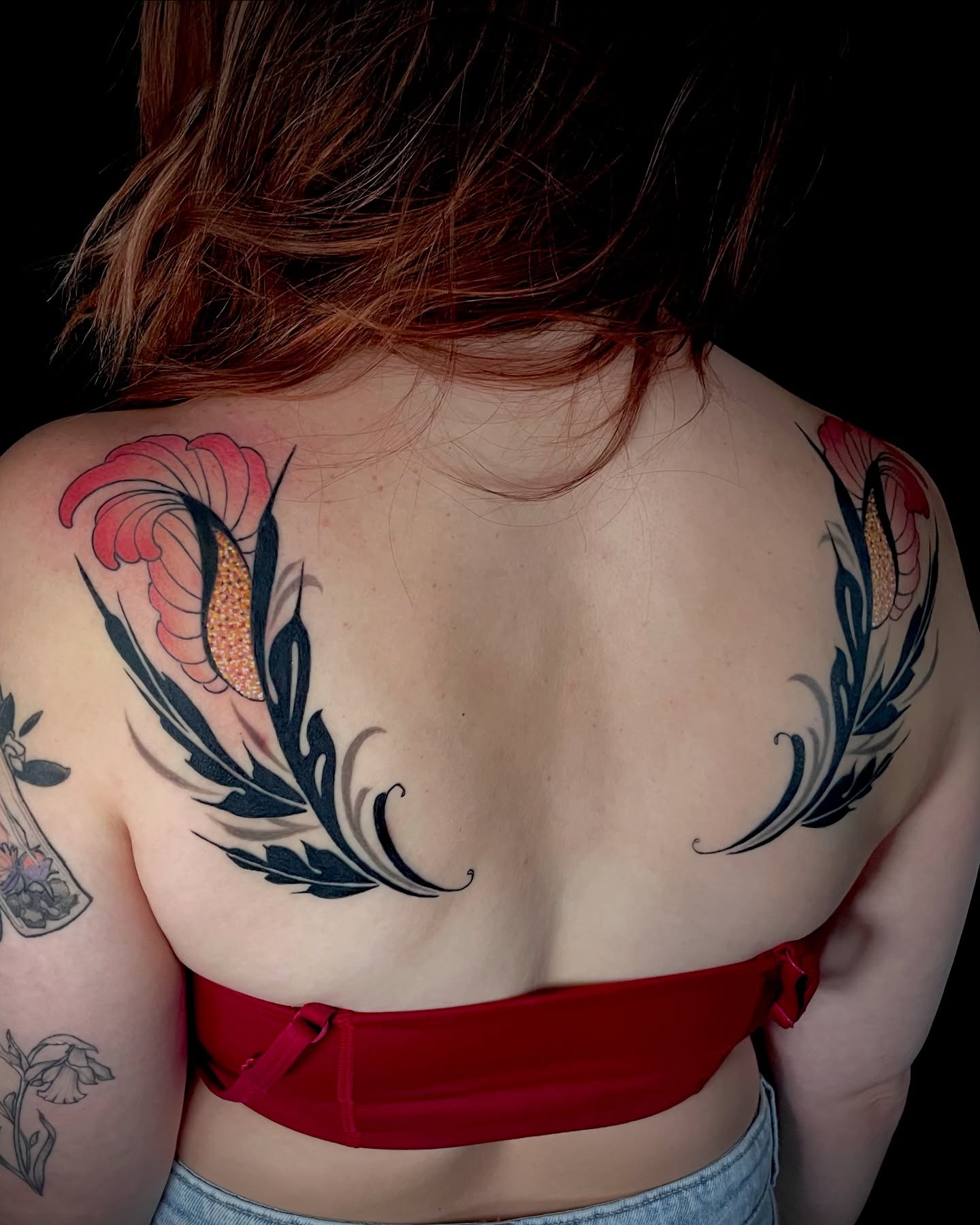 Feather and flower neo-traditional tattoo on the back by Laura Babsie