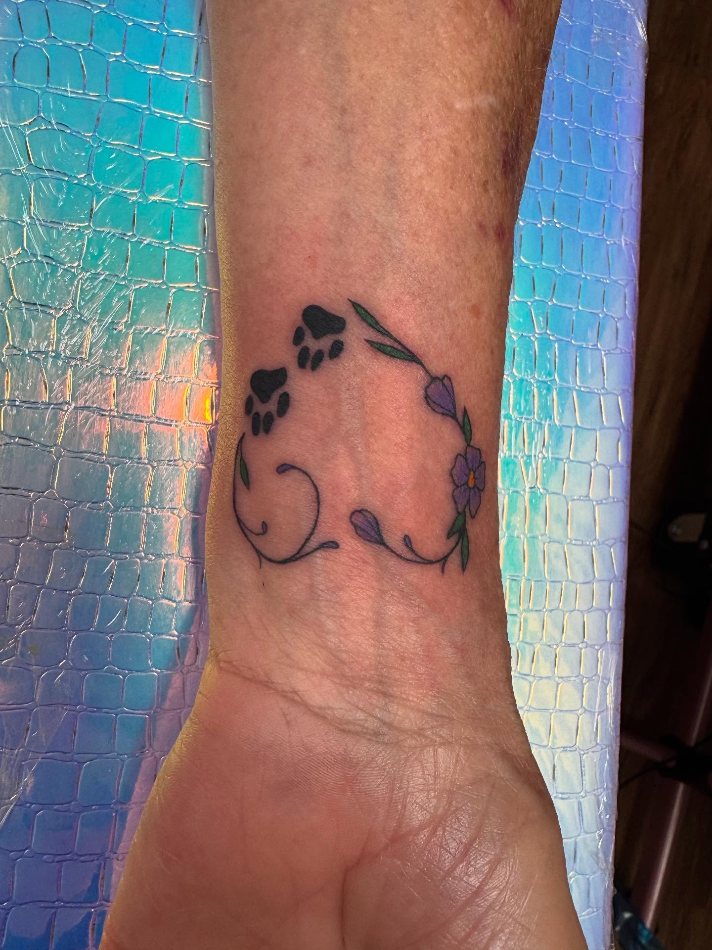 Paw prints and flowers dotwork tattoo on the forearm by McKenna Chalifoux