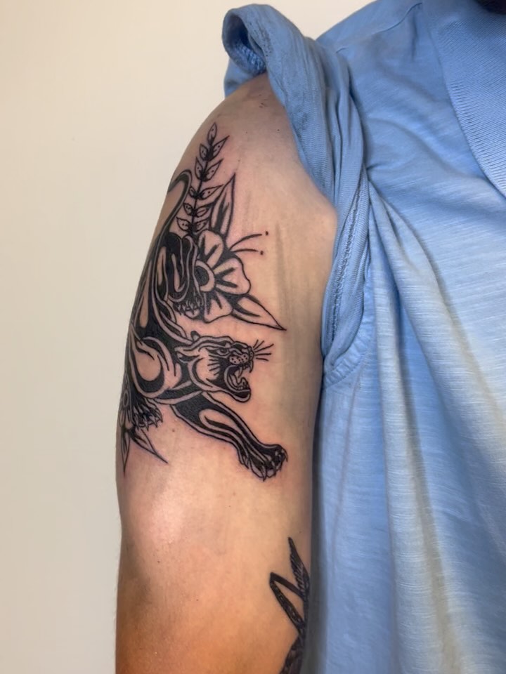 Panther and floral black and grey tattoo on the shoulder by Emmie Turner