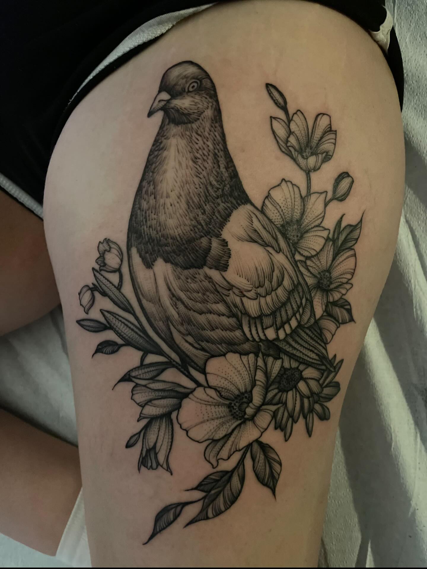 Pigeon and flowers realism tattoo on the thigh by Jacob Kearney