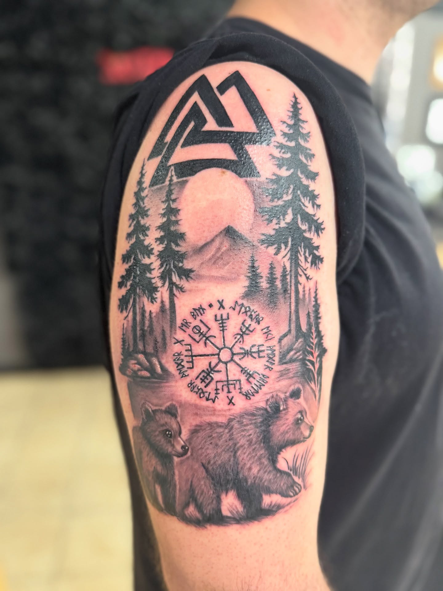 Forest scene with bears realism tattoo on the upper arm by Tattoo Artist