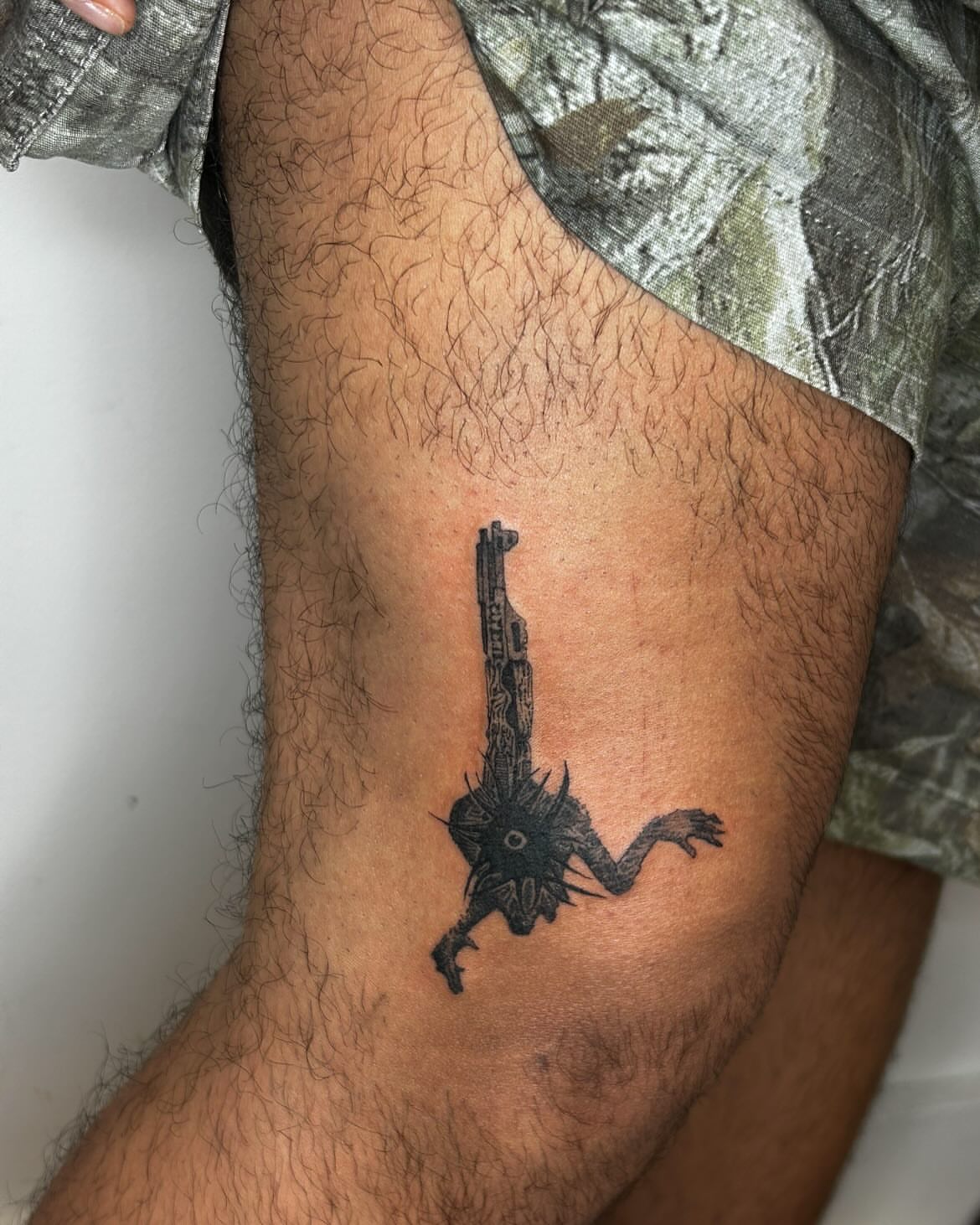 Gun with creature black and grey tattoo on the forearm by Jadin Nichols