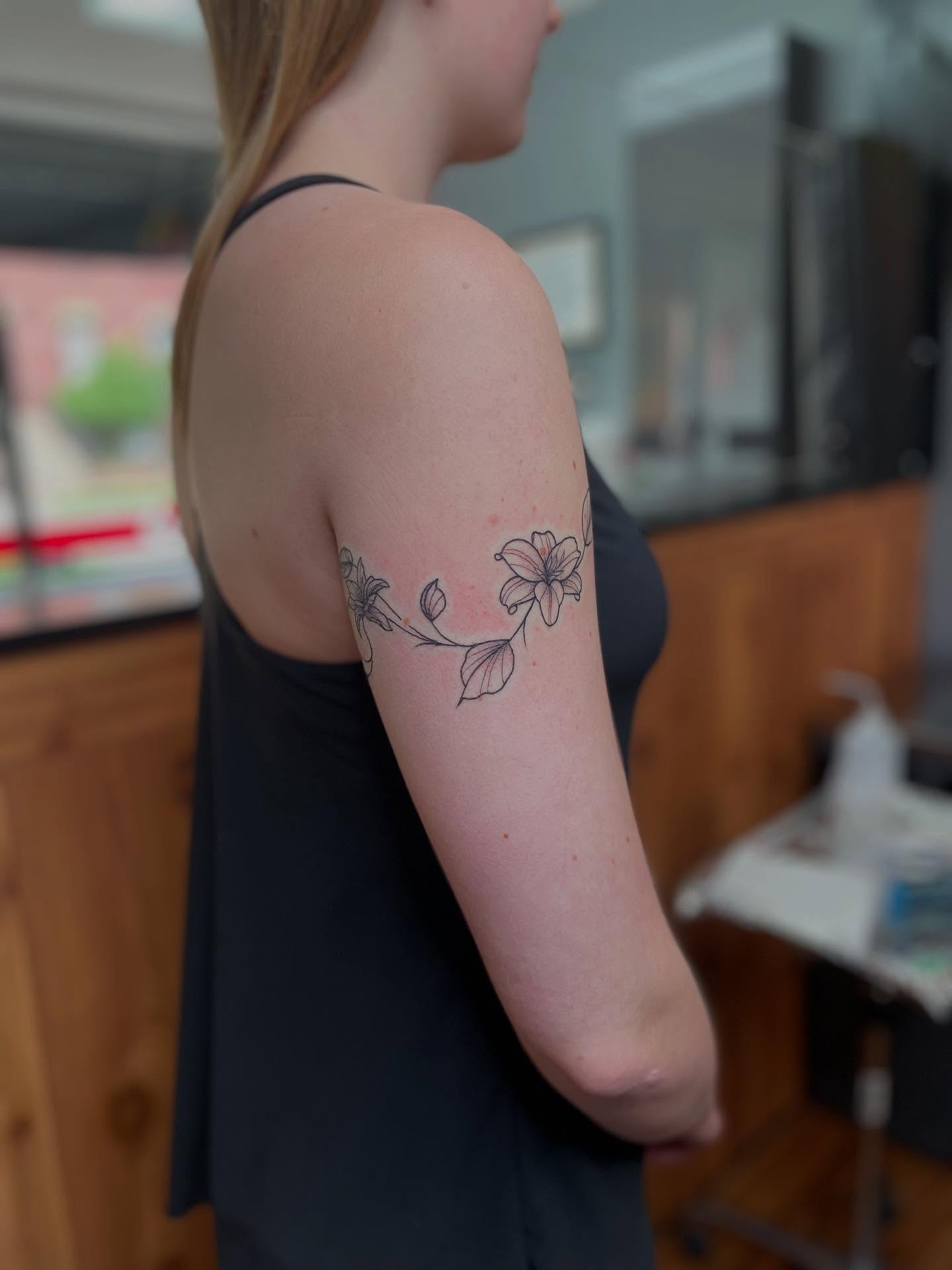 Floral design fine line tattoo on the upper arm by Anna sabrowsky