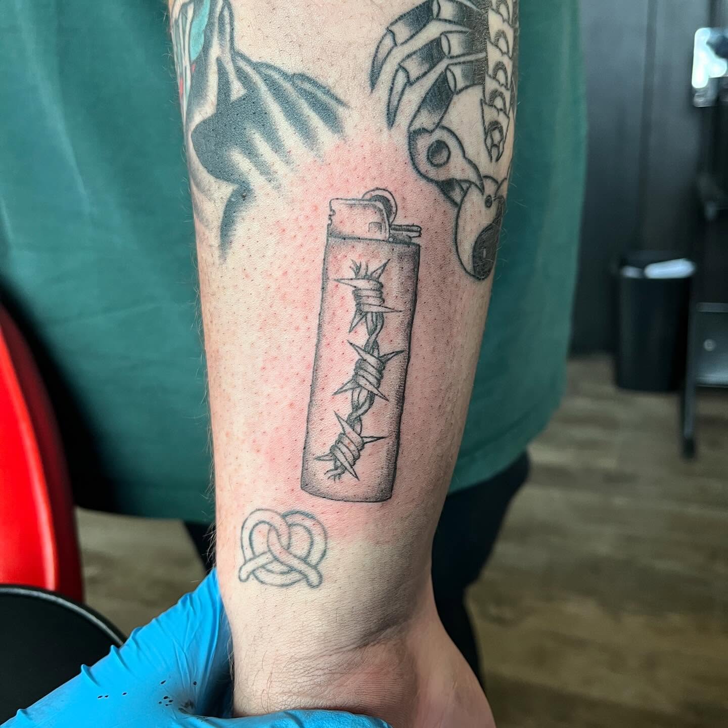 Lighter with barbed wire black and grey tattoo on the forearm by sarah