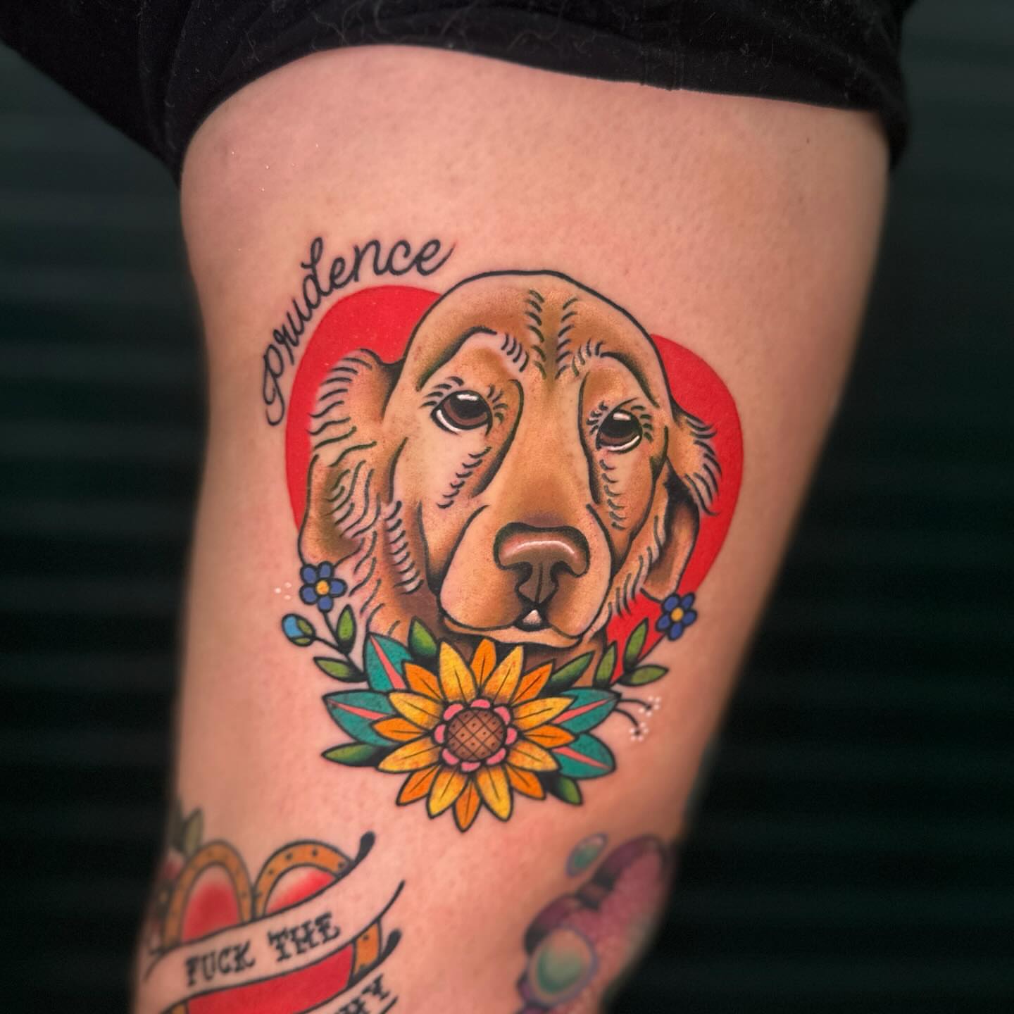Dog with floral wreath American traditional tattoo on the thigh by Annah Lea