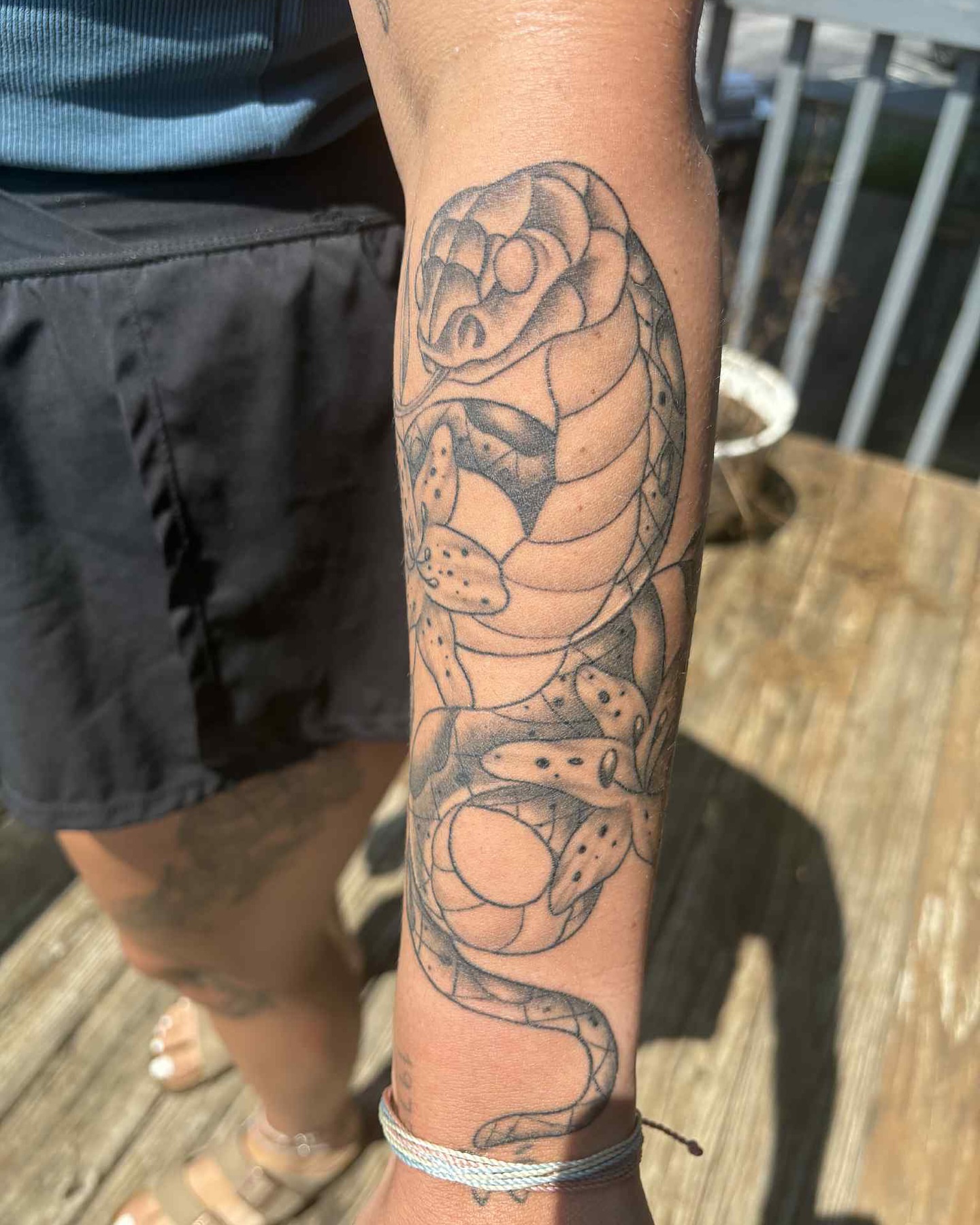 Snake and peony black and grey tattoo on the forearm by Brandon Anderson