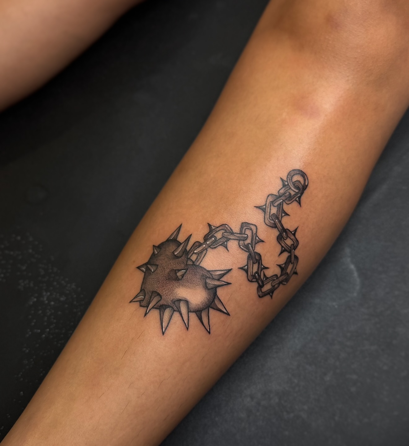 Spiked ball and chain black and grey tattoo on the forearm by Dee, San Diego, California