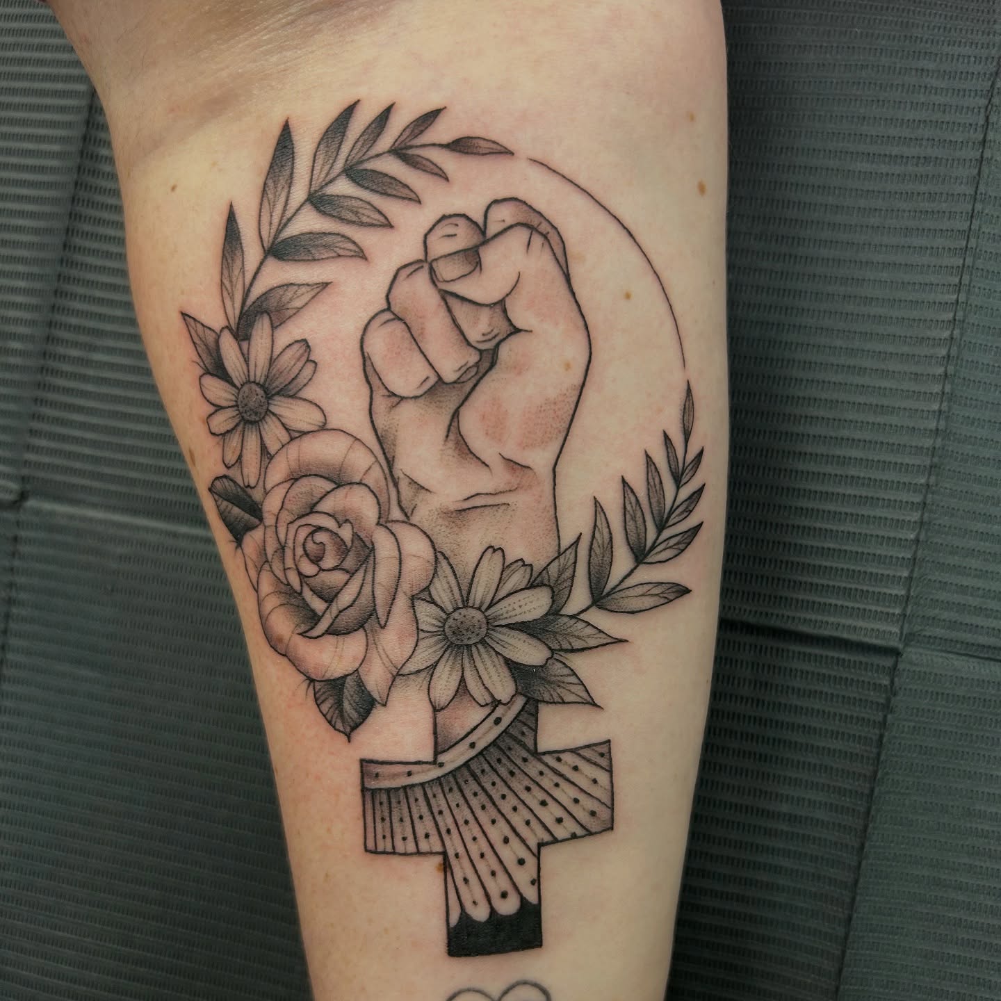 Fist and flowers dotwork tattoo on the forearm by Patricia Cunningham