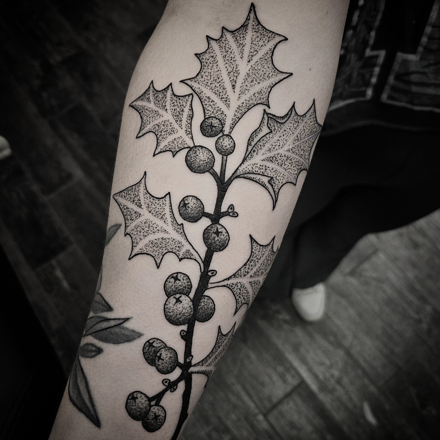 Holly branch dotwork tattoo on the forearm by Kirk George