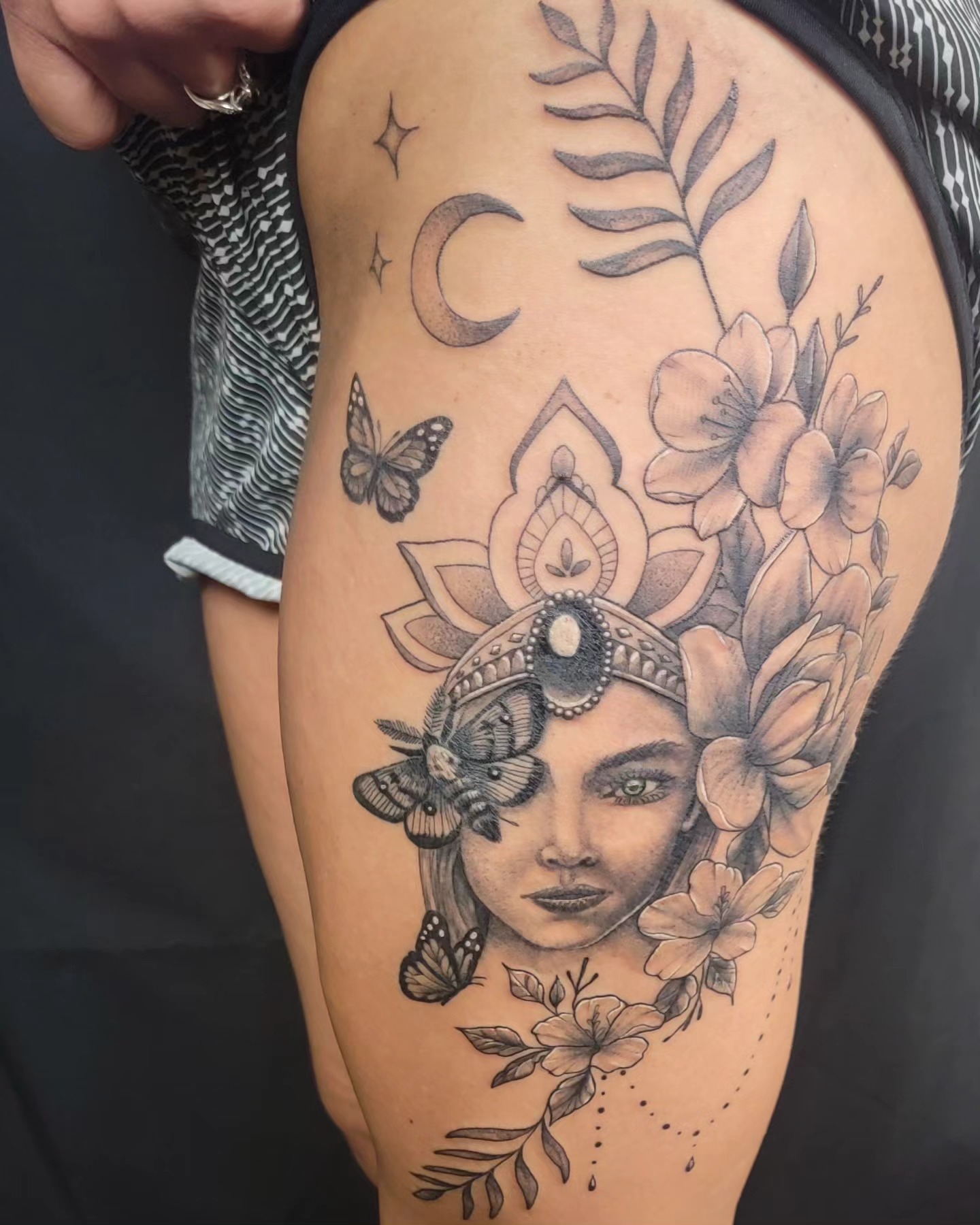 Woman with flowers and moths realism tattoo on the thigh by Hatchetfoot Art