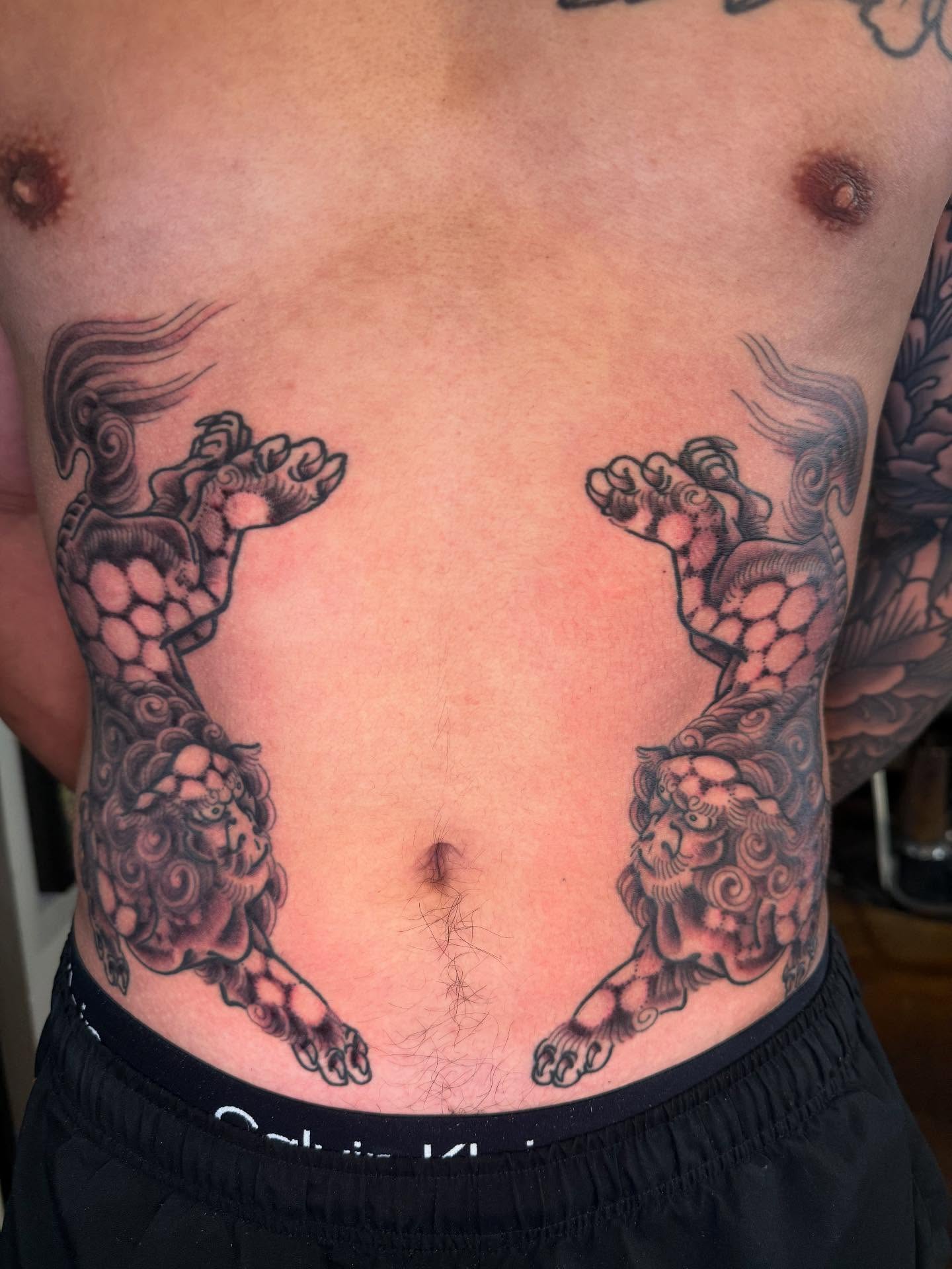Lion-like creatures black and grey tattoo on the torso by Mike Diamond