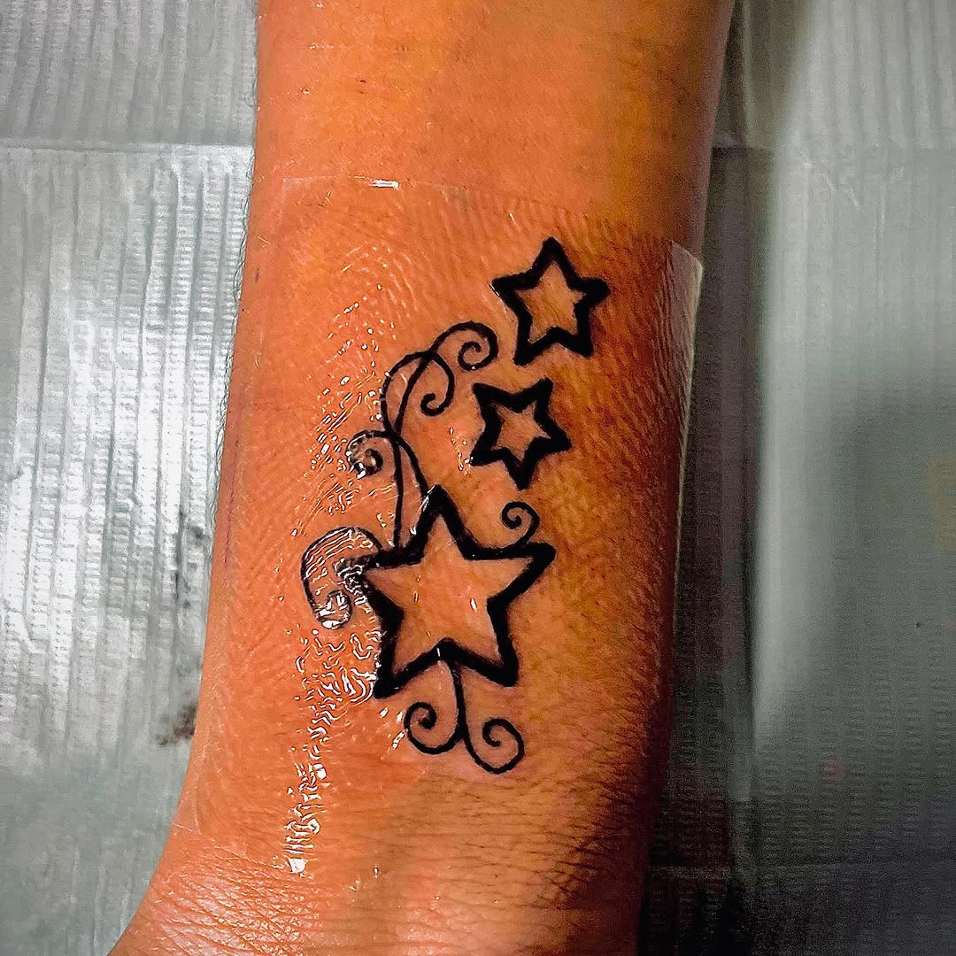 Stars with swirls fine line tattoo on the forearm by Eunoia Tattoos