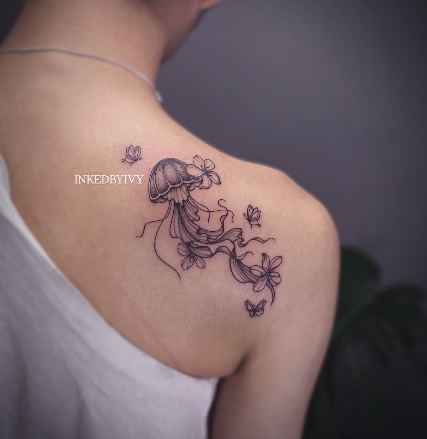 Jellyfish and flowers realism tattoo on the shoulder by IVY