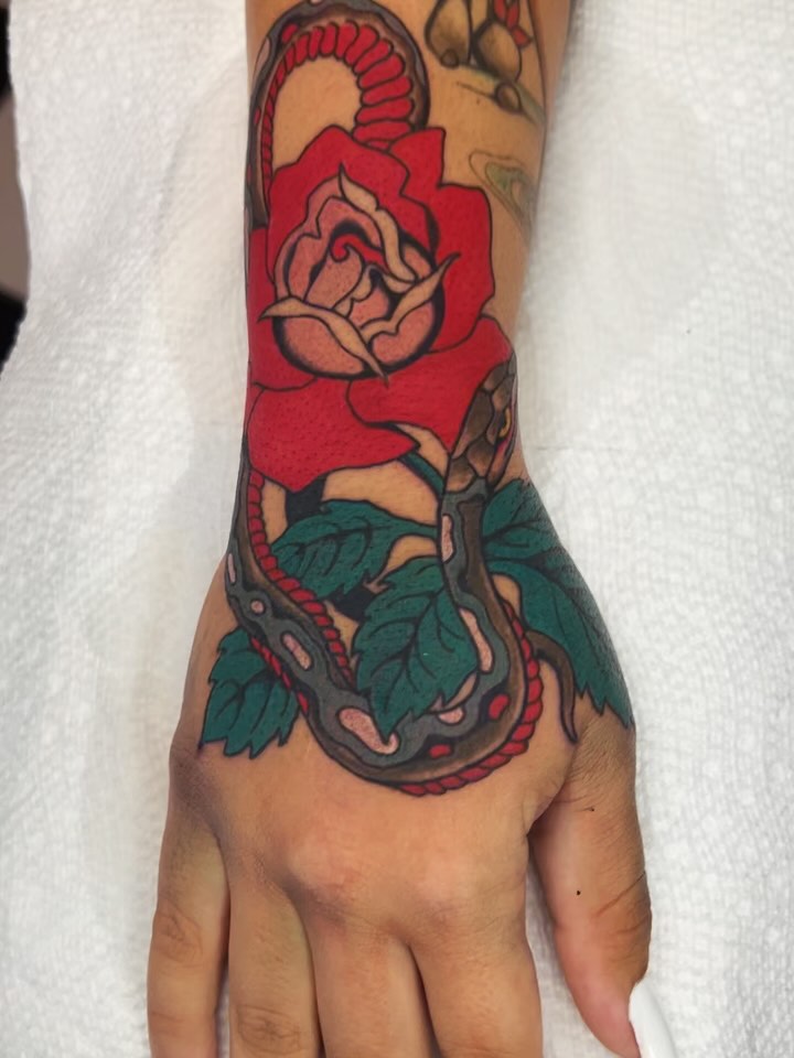 Snake and rose American traditional tattoo on the hand by superteal