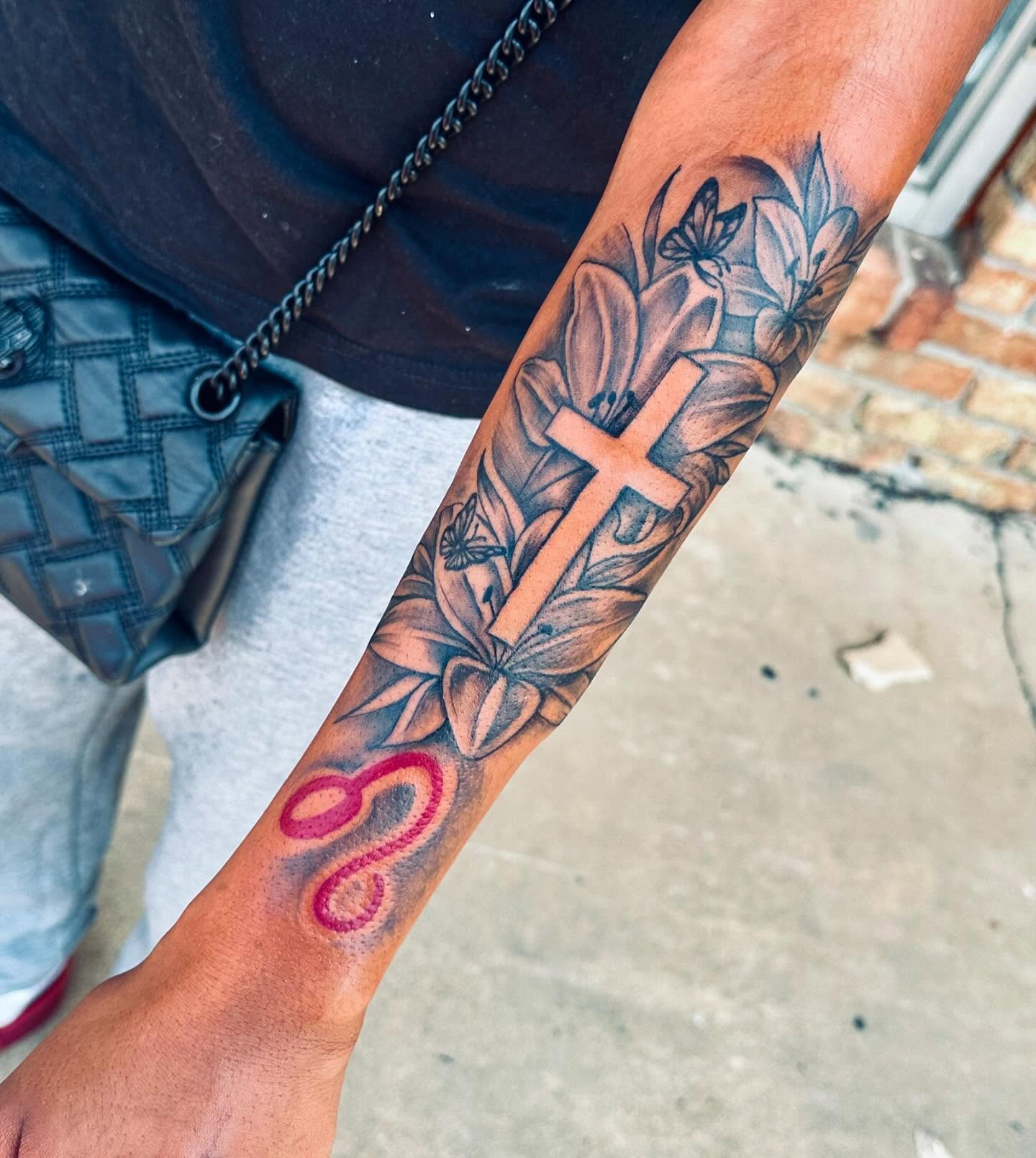 Cross and flowers black and grey tattoo on the forearm by GrindHard Quen