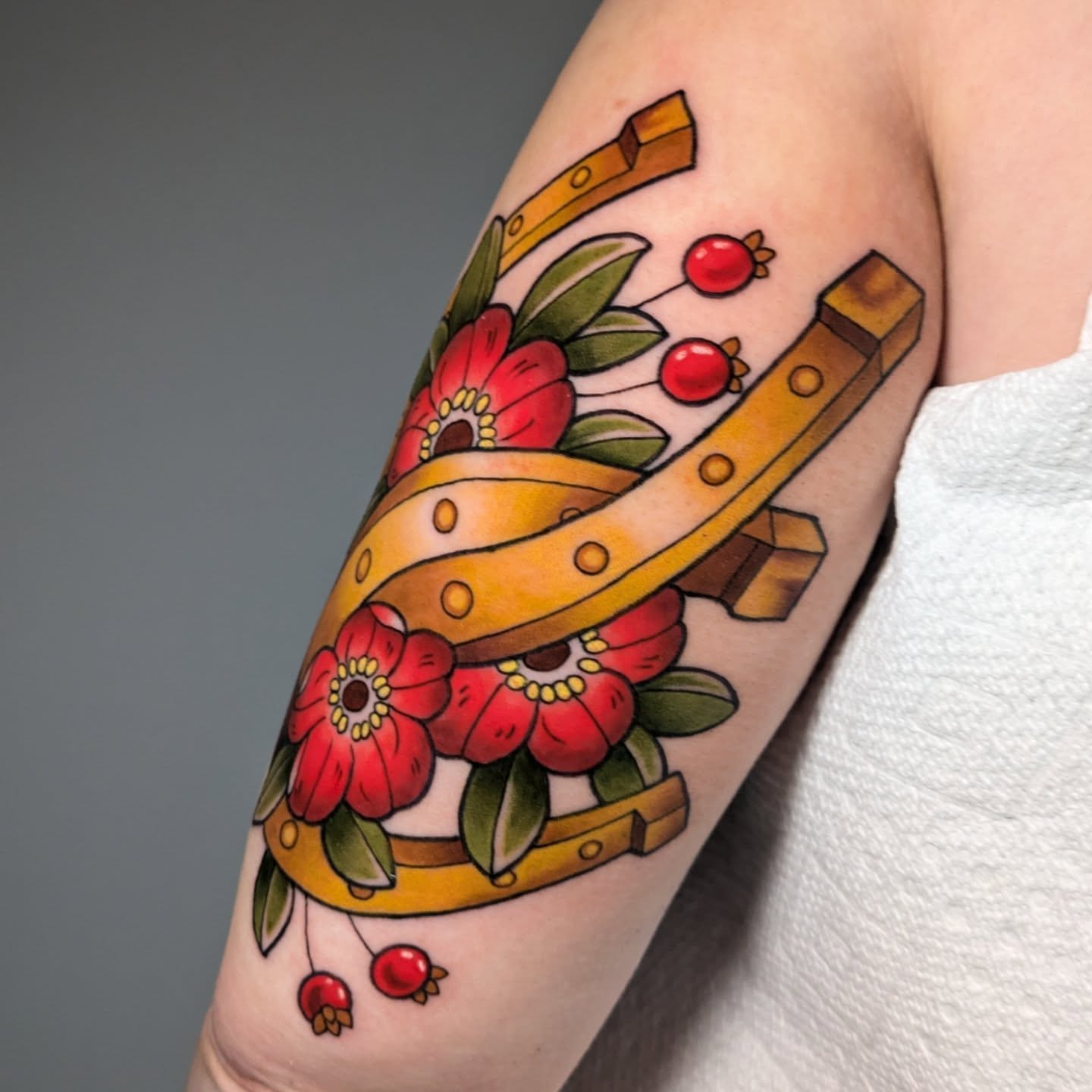 Horseshoe and flowers American traditional tattoo on the forearm by Ellie