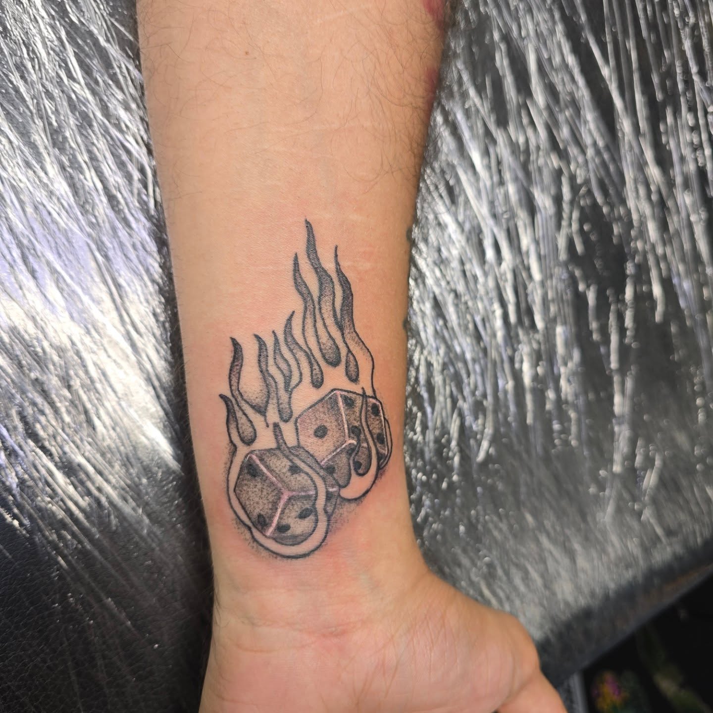 Flaming dice dotwork tattoo on the forearm by Karen Cain