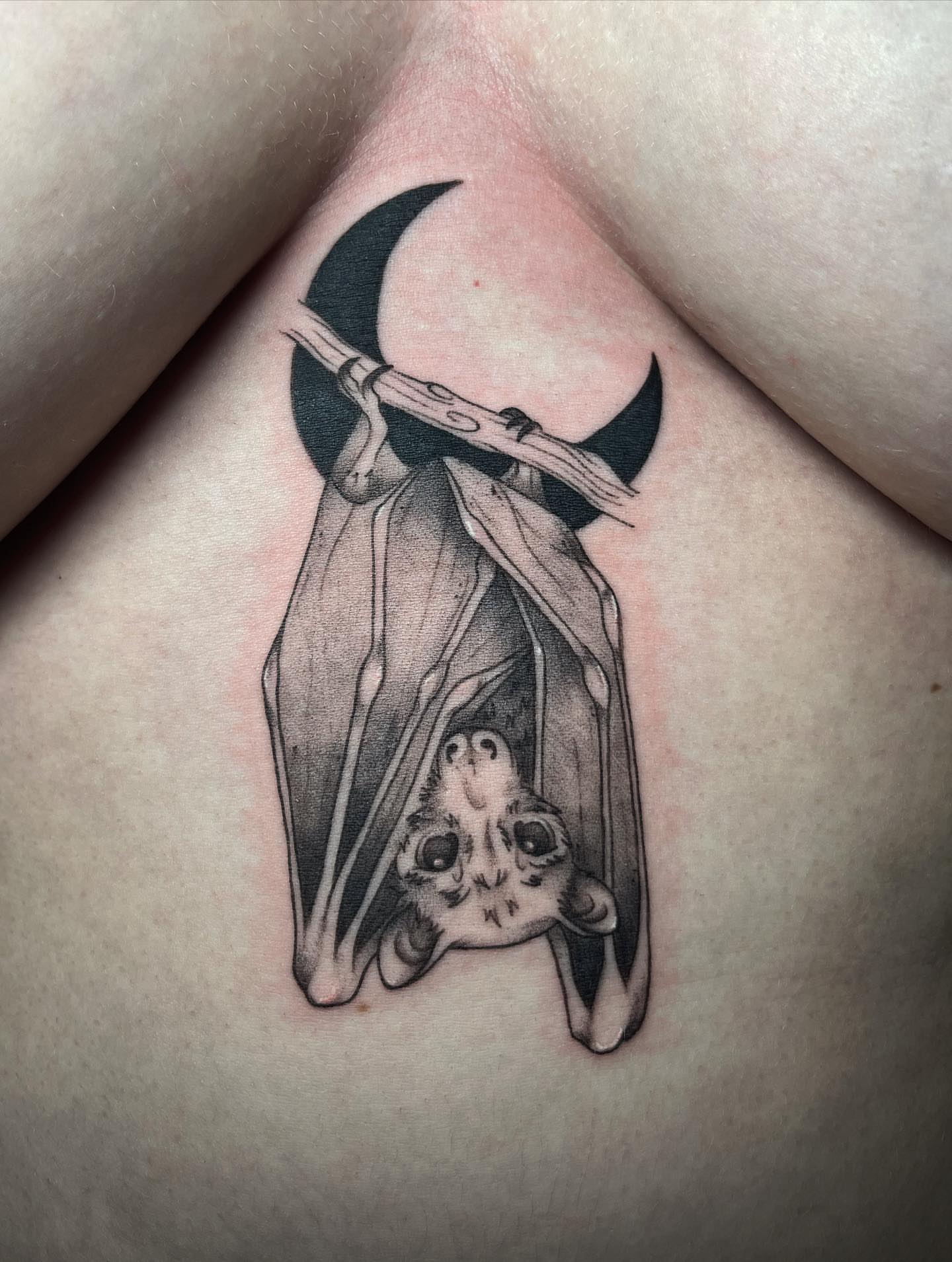 Bat hanging from crescent moon realism tattoo on the torso by Ty’s Tattoos