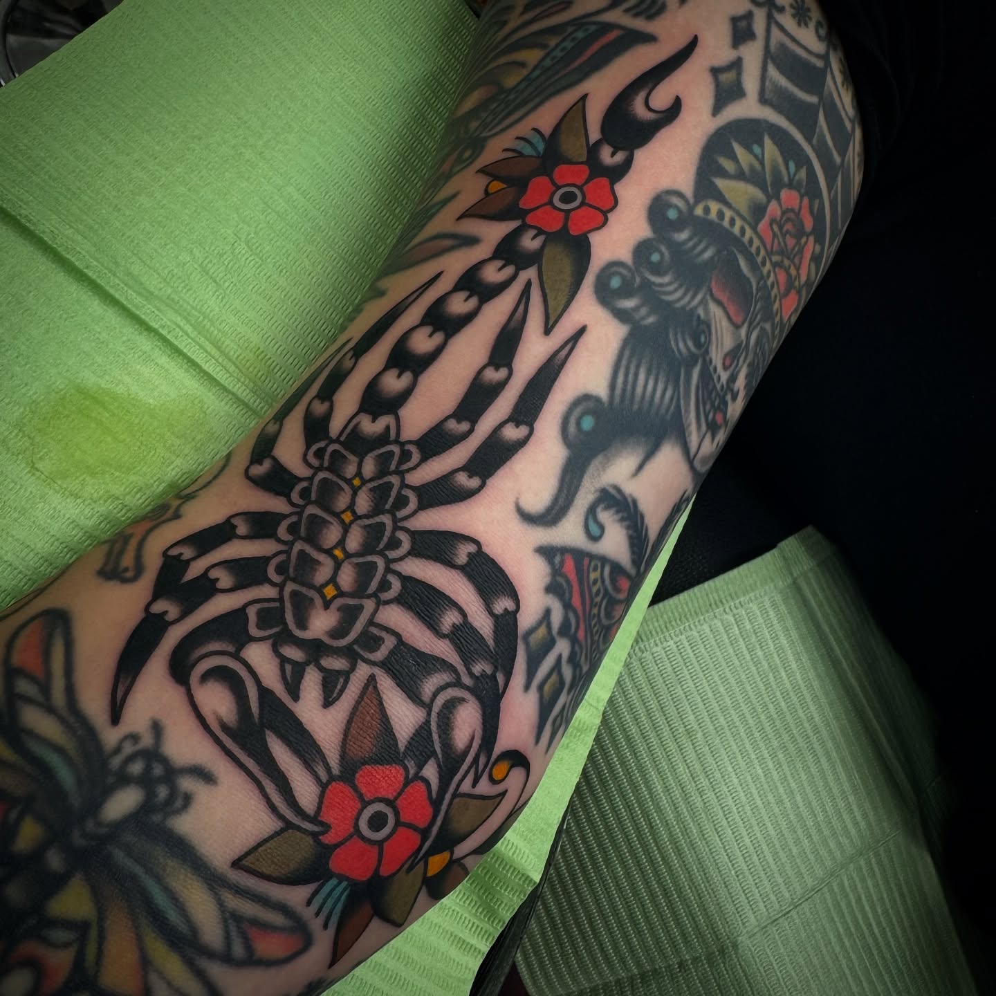 Scorpion and flowers American traditional tattoo on the forearm by Rogelio Robles