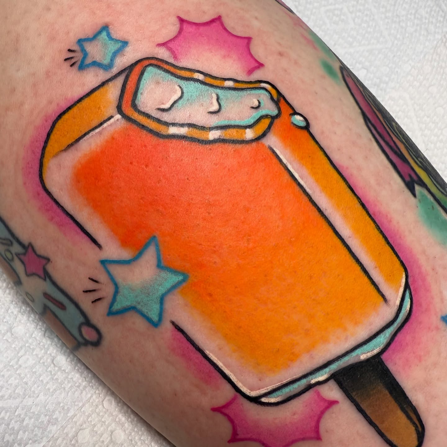 Orange popsicle new school tattoo on the forearm by vic