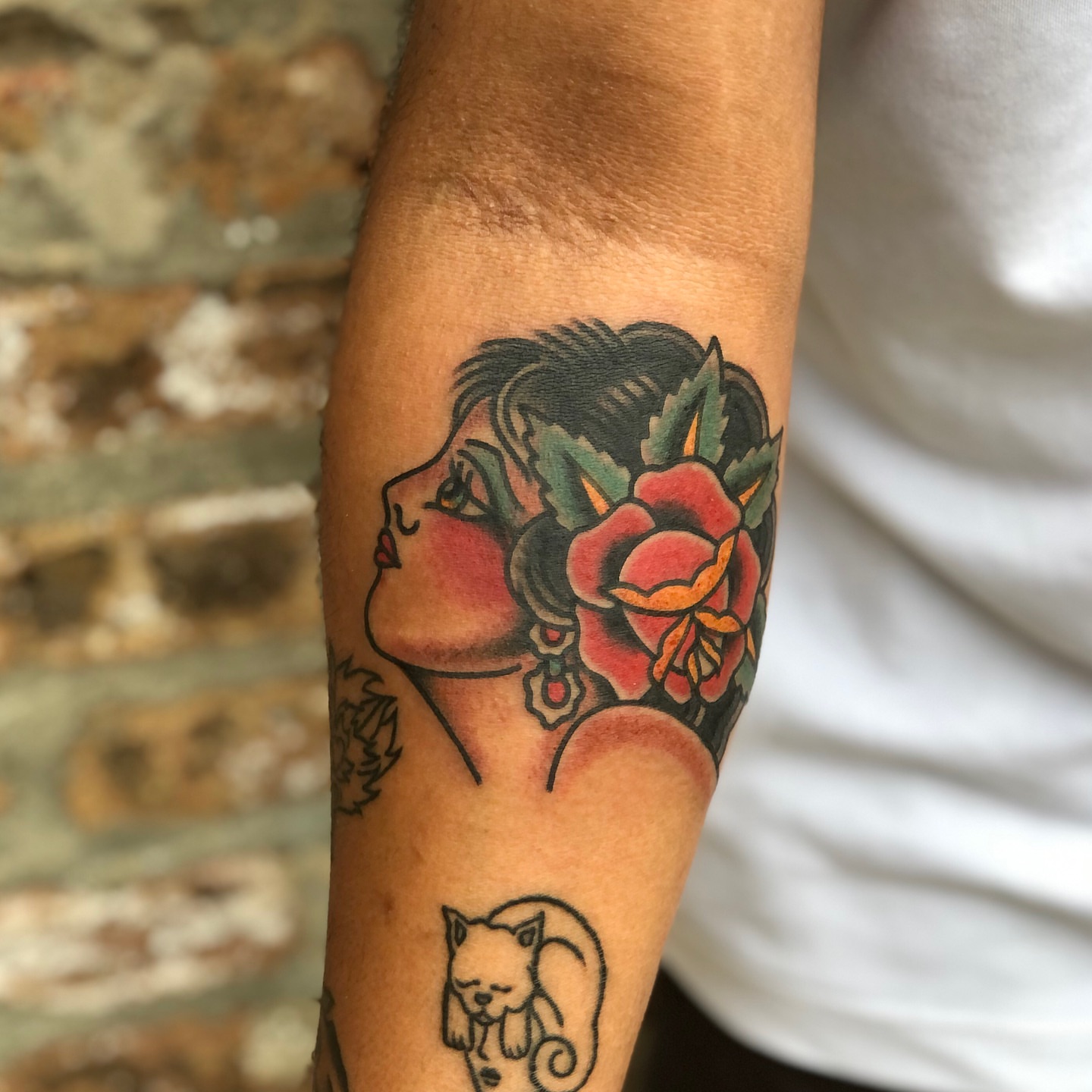Woman with flower American traditional tattoo on the forearm by Nick Sharratt, Chicago, Illinois