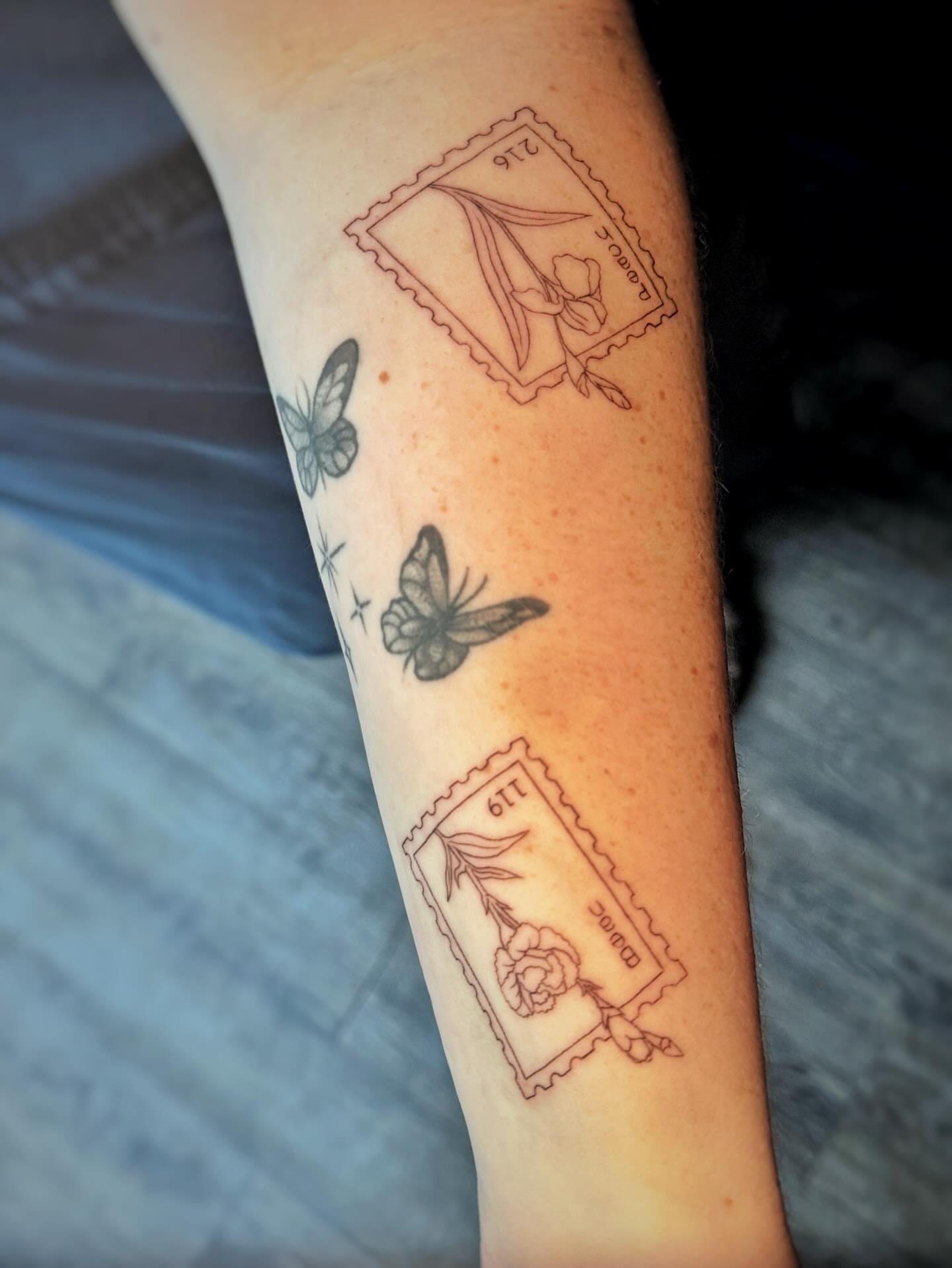 Postage stamp and butterflies black and grey tattoo on the forearm by Sarah Flemon