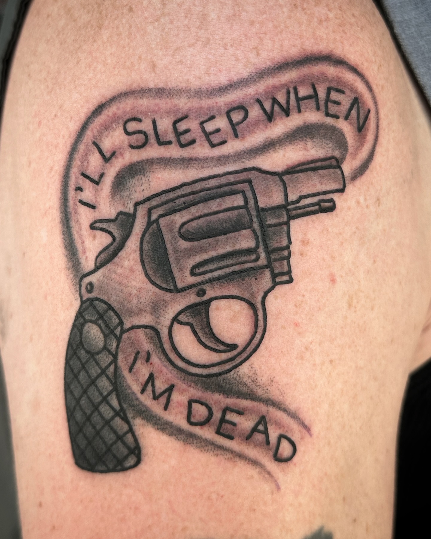 Revolver with text black and grey tattoo on the thigh by Chris Blanchard