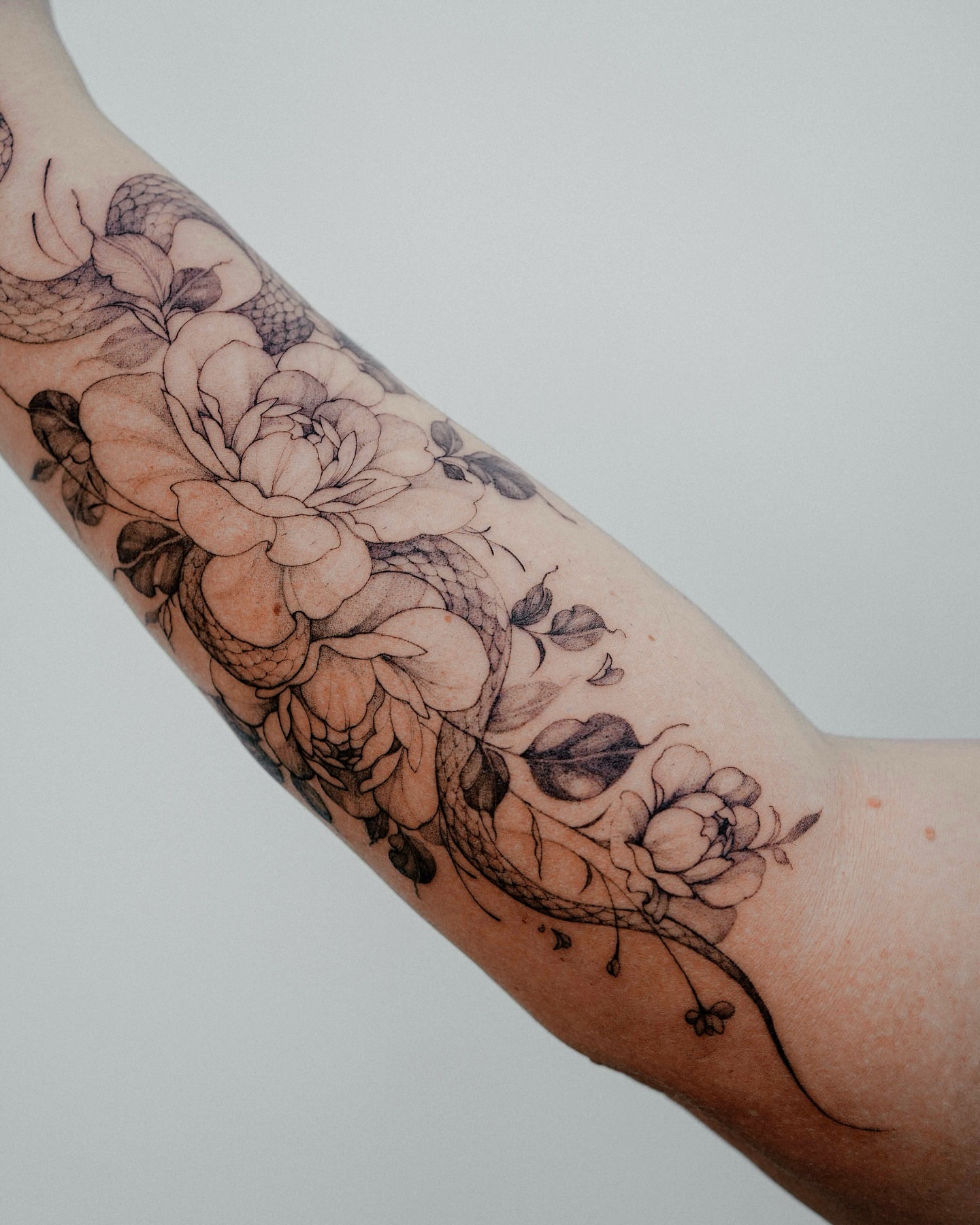 Snake and peony black and grey tattoo on the forearm by Yeonji