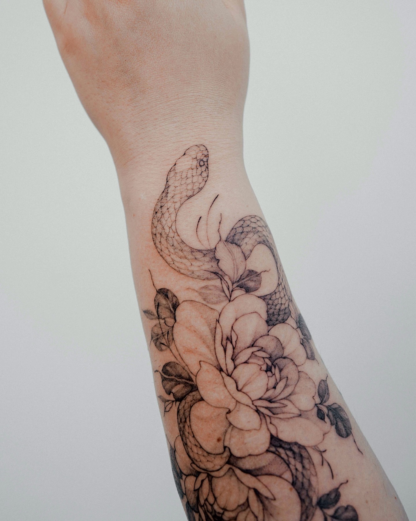 Snake and peony realism tattoo on the forearm by Yeonji