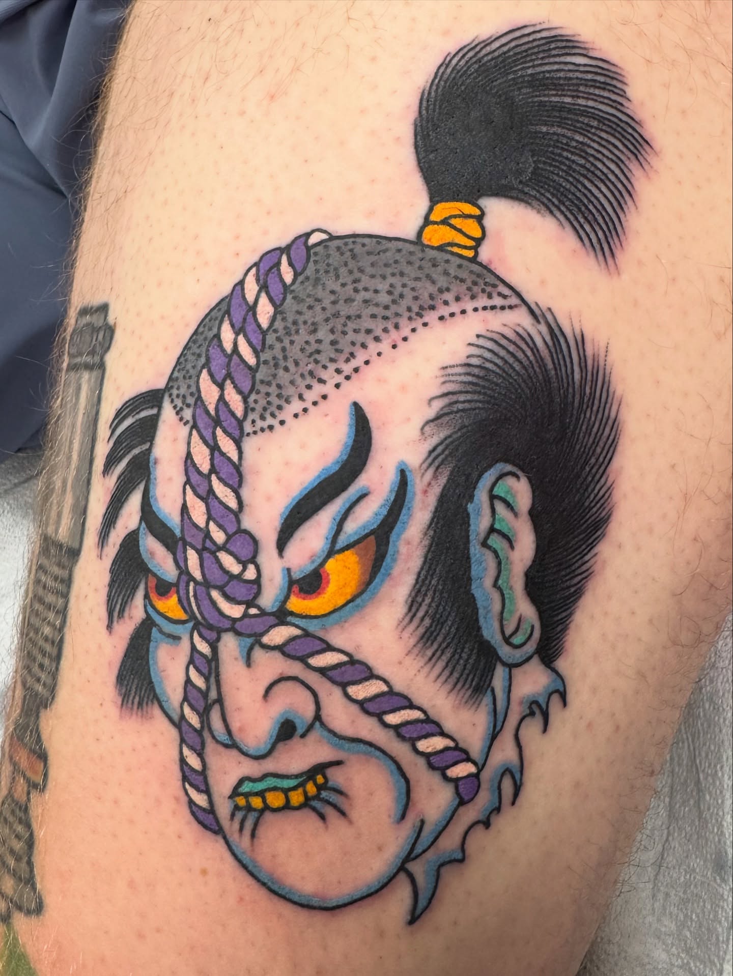 Japanese mask American traditional tattoo on the thigh by Timothy Wood